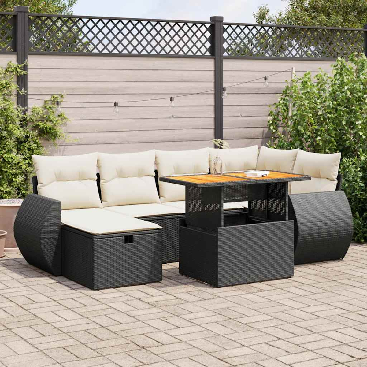 Outdoor-Möbelset aus schwarzem Korbgeflecht mit Tisch. Es gibt Gras und einen Zaun.