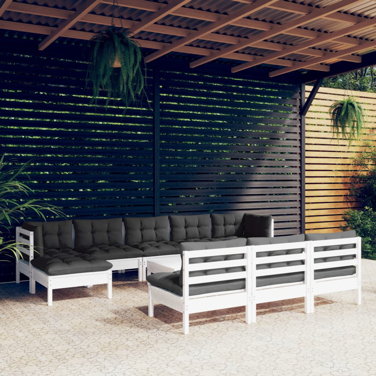 Weiß gerahmtes Gartenmöbel-Set mit dunkelgrauen Kissen. Szene unter einer Holzpergola mit Pflanzen.