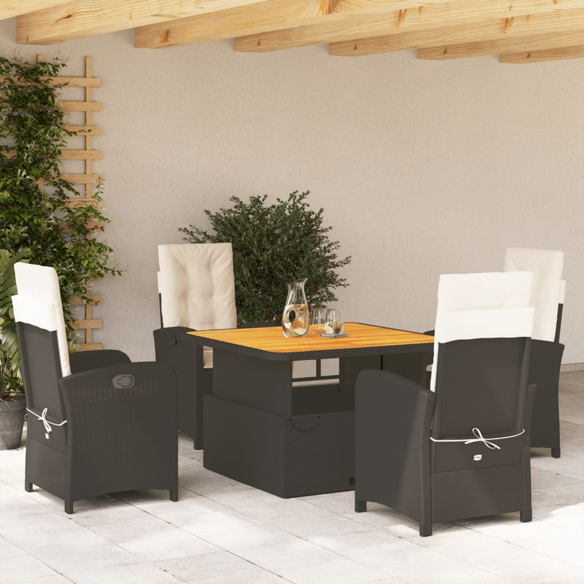Terrassenmöbel-Set mit schwarzen Korbmöbeln, einem Holztisch und weißen Kissen.