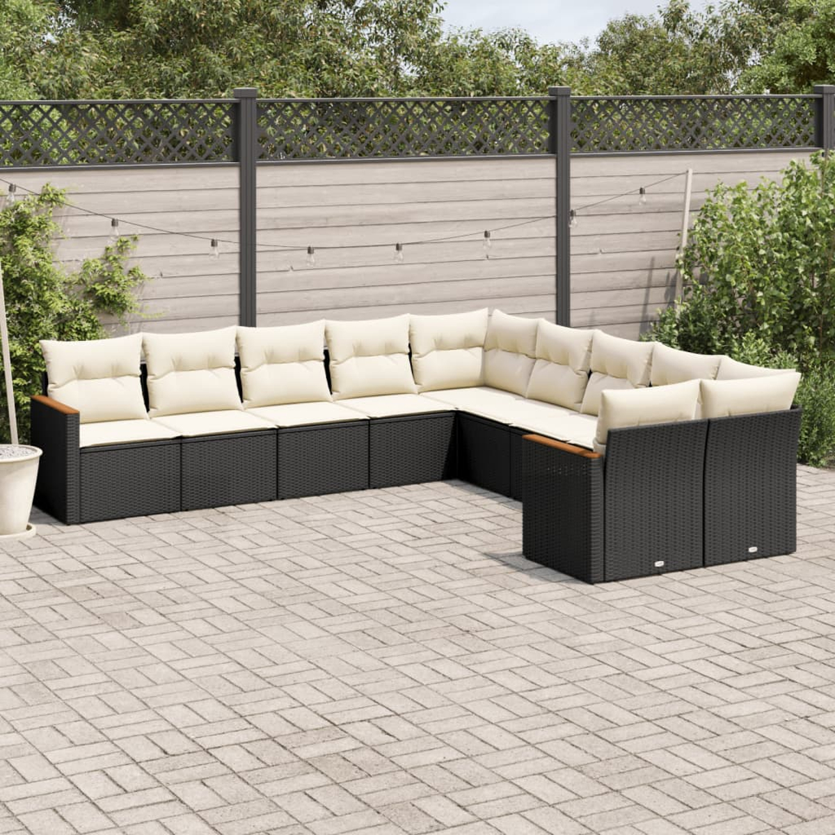 Schwarzes Outdoor-Ecksofa mit beigen Kissen. Auf einer gepflasterten Terrasse.