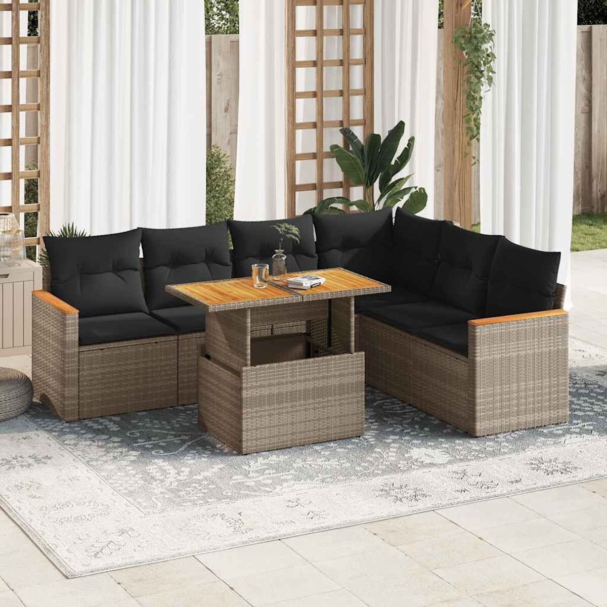 Gartenmöbel-Set mit hellbraunem Webrahmen, schwarzen Kissen und einem Holztisch. Auf einem hellen Teppich.