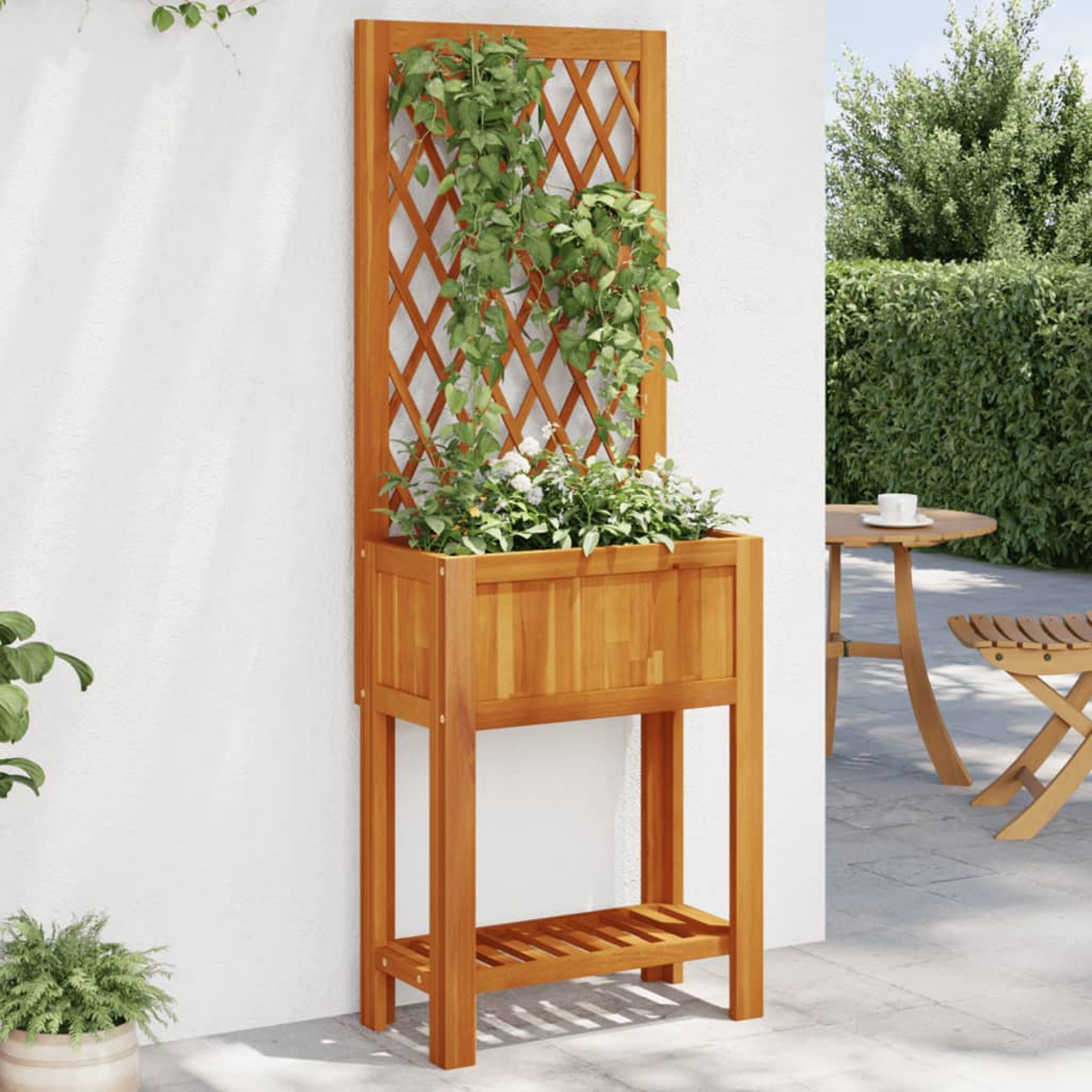 Ein Holzpflanzer mit Spalier, voller grüner Pflanzen und weißer Blumen, vor einer weißen Wand.