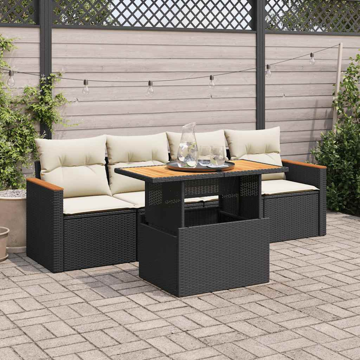 Seccional exterior con mesa elevable, mimbre negro, cojines beige, en patio de ladrillos.