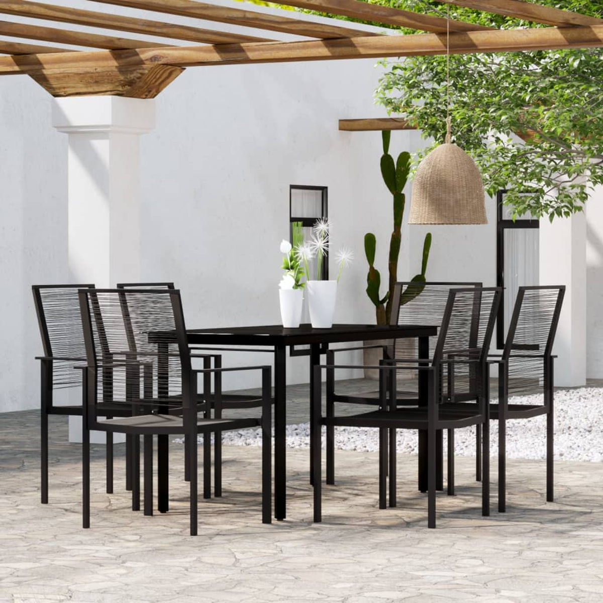 Essgruppe im Freien mit schwarzen Stühlen und einem Tisch, vor einer weißen Wand und einer Pergola.