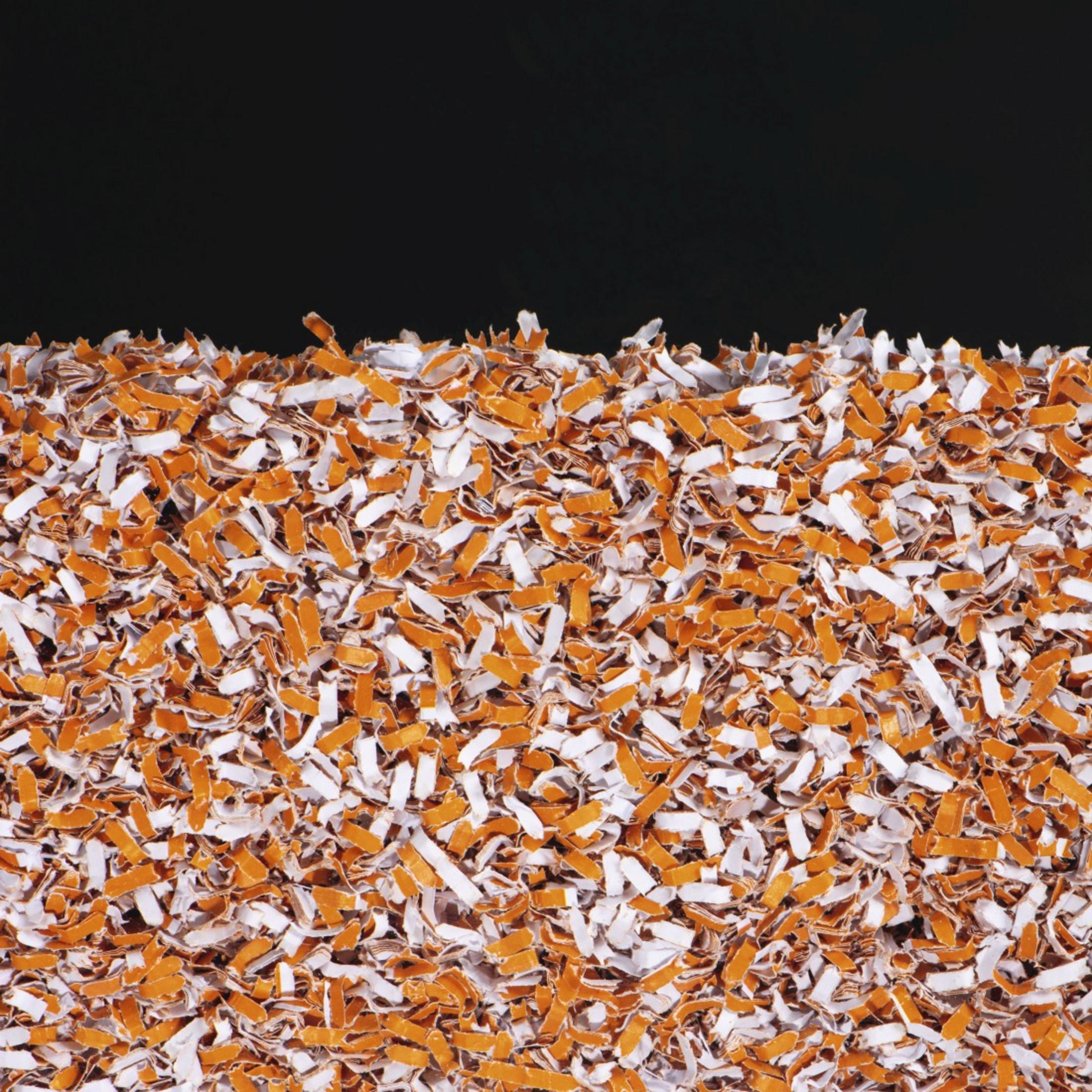 Zbliżenie pociętego pomarańczowo-białego papieru, wypełniającego kadr na czarnym tle.