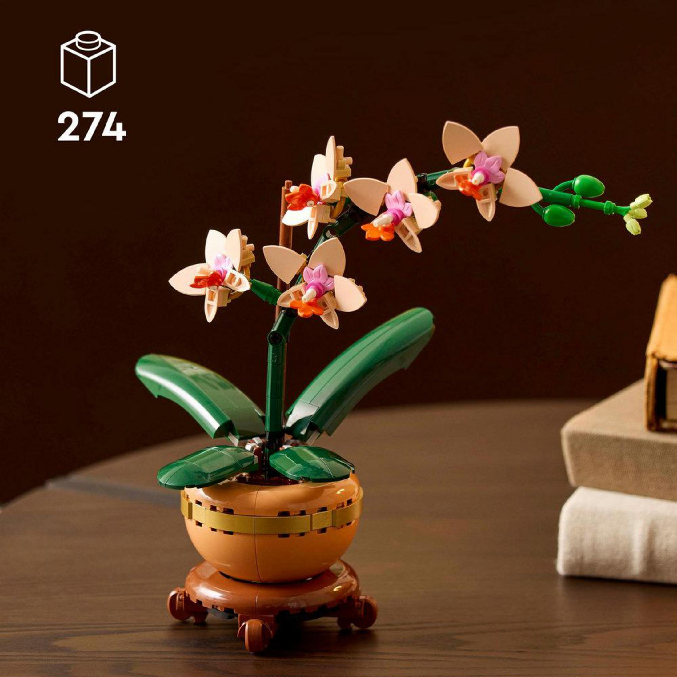 Una planta de orquídea Lego está en una maceta, con hojas y flores.
