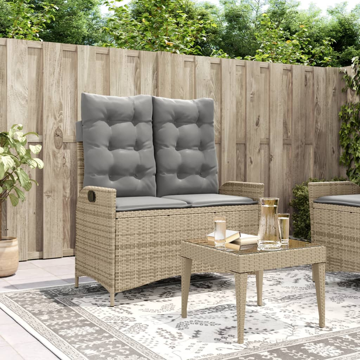 Geflochtenes Gartenmöbel-Set mit Sofa, Tisch und Holzzaun im Hintergrund.