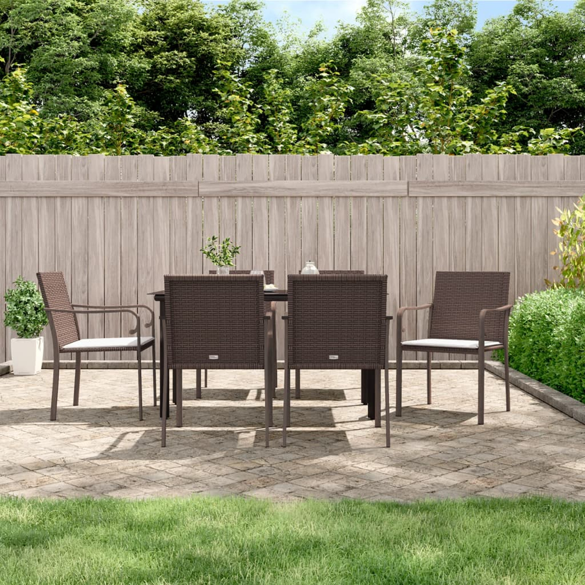 Essgruppe im Freien auf einer Terrasse, mit Zaun und Bäumen im Hintergrund.