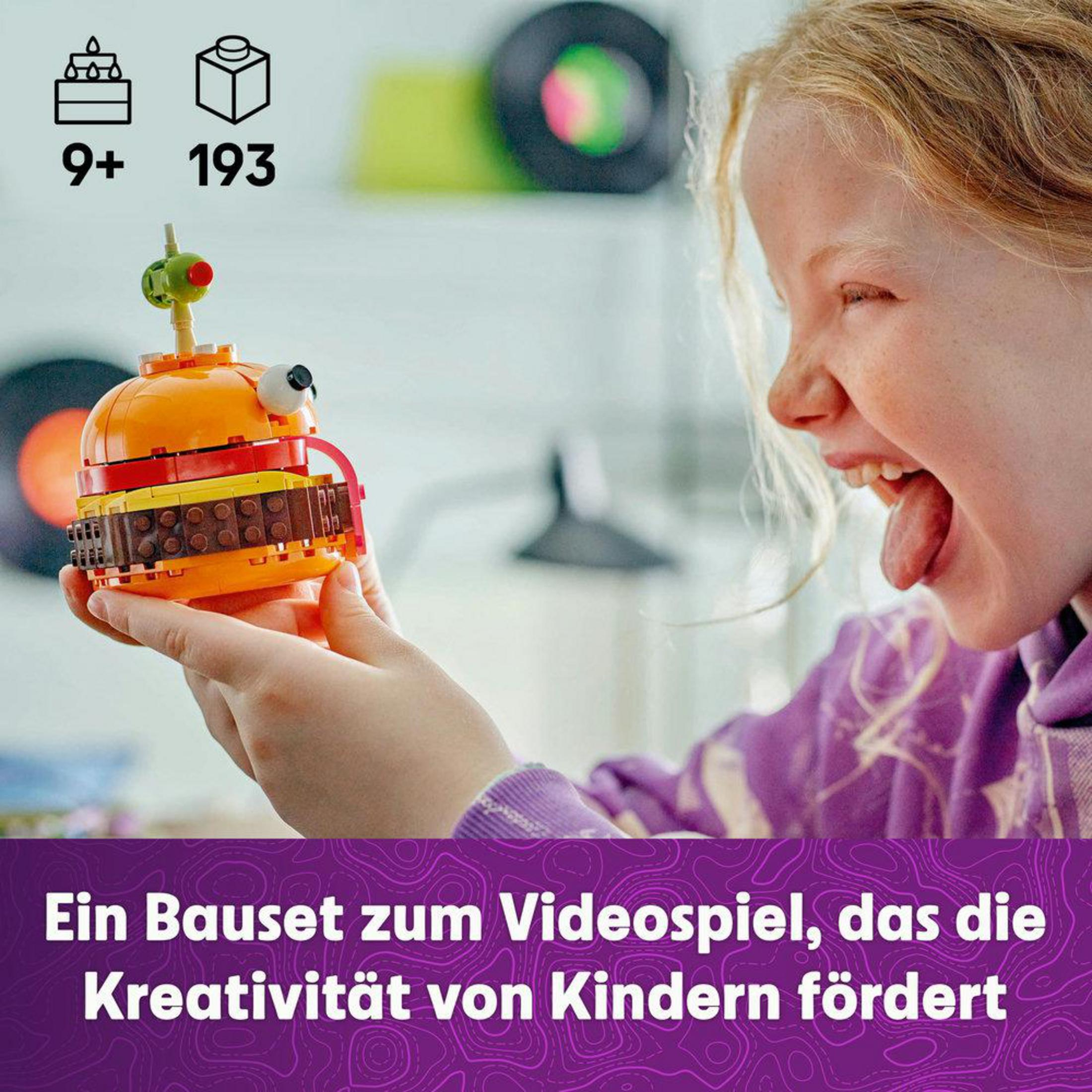 Ein Mädchen hält einen Spielzeugburger. Das Spielzeug hat Schichten, und das Mädchen streckt die Zunge heraus. Hintergrund hat Schallplatten.