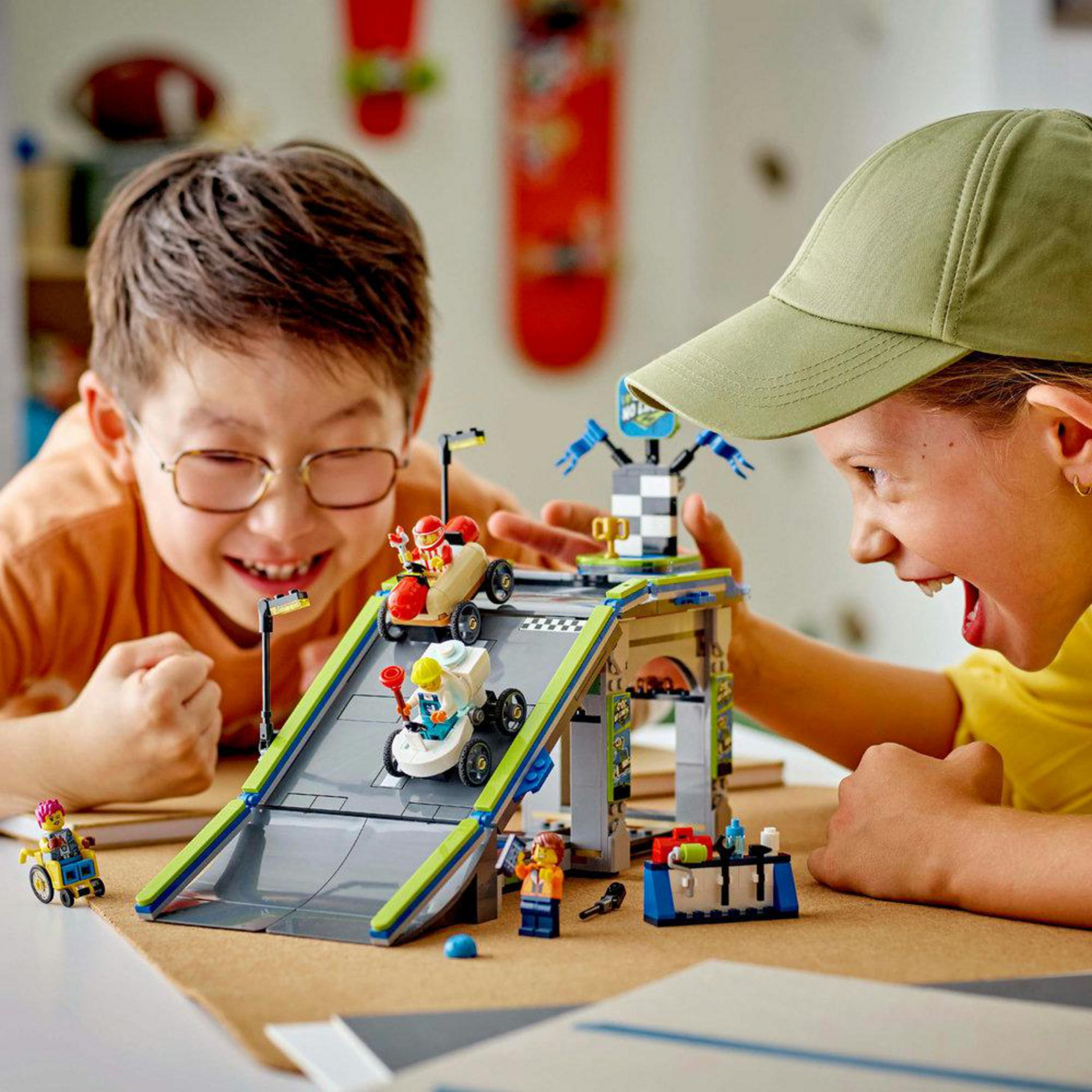 Dos niños jugando con una rampa Lego City. Uno tiene gorra verde.