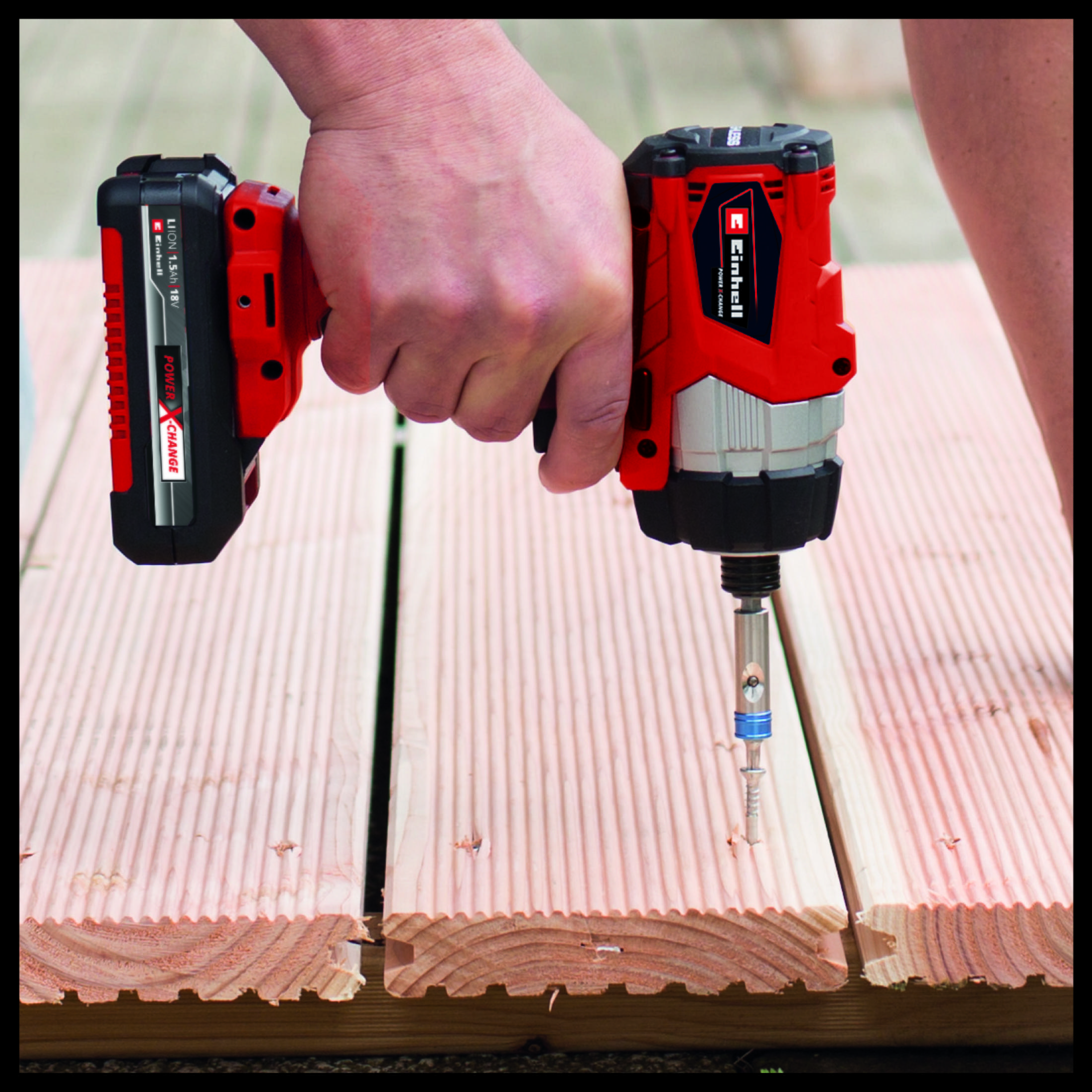 Osoba używająca czerwono-czarnej wiertarki akumulatorowej do wkręcania w drewniane deski.