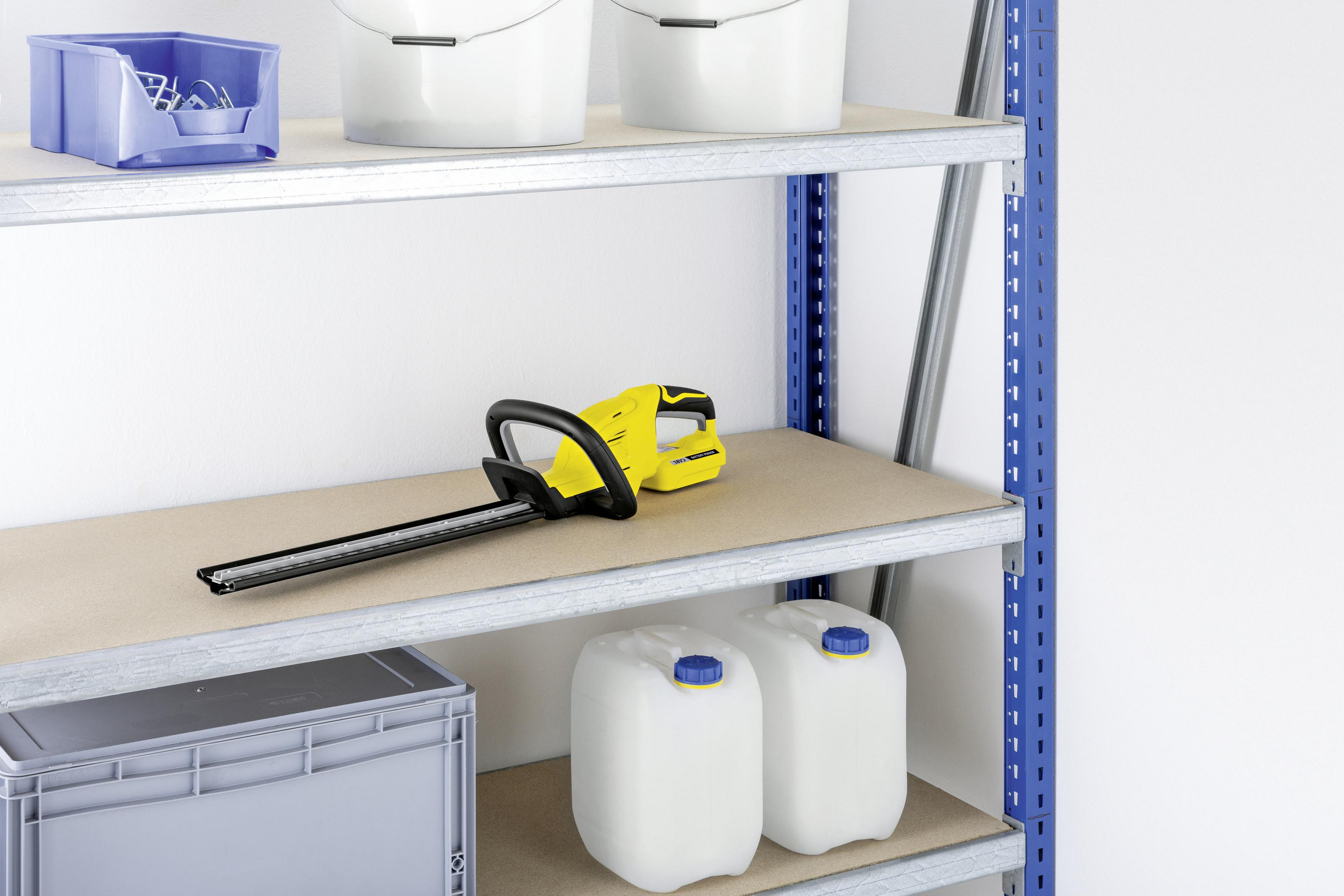 Regał z żółtymi nożycami do żywopłotu i innymi przedmiotami. Widoczne białe ściany i niebieskie podpory półek.