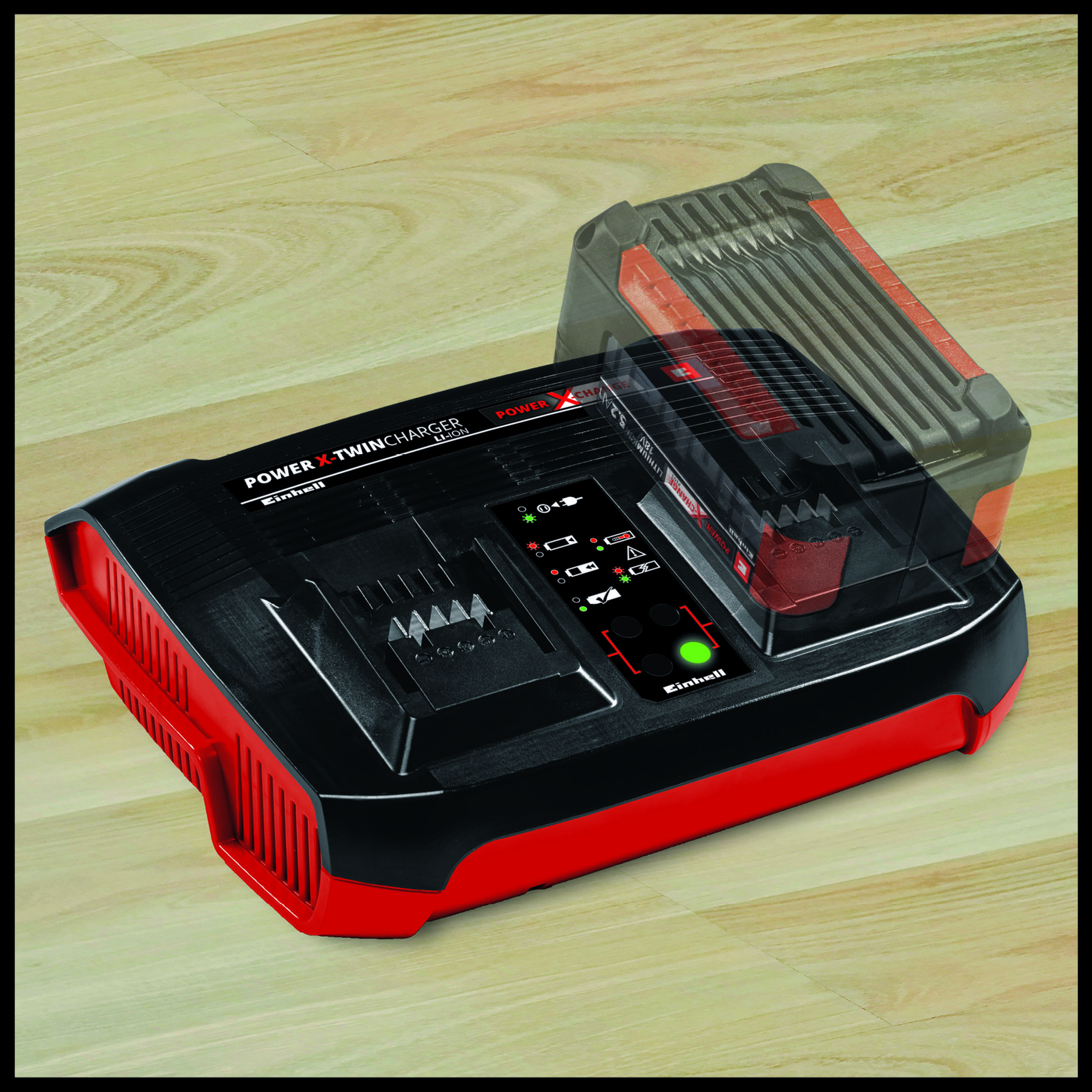 Ein schwarz-rotes Einhell Power-X Twincharger mit eingelegtem Akku. Der Hintergrund ist ein Holzboden.