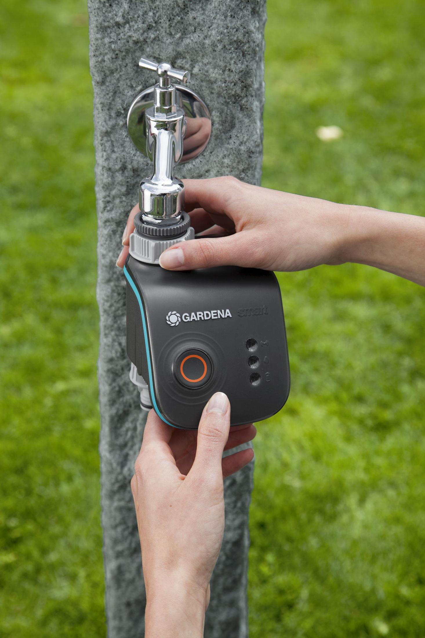 Hände befestigen ein GARDENA Smart Wassersteuerungsgerät an einem Wasserhahn.
