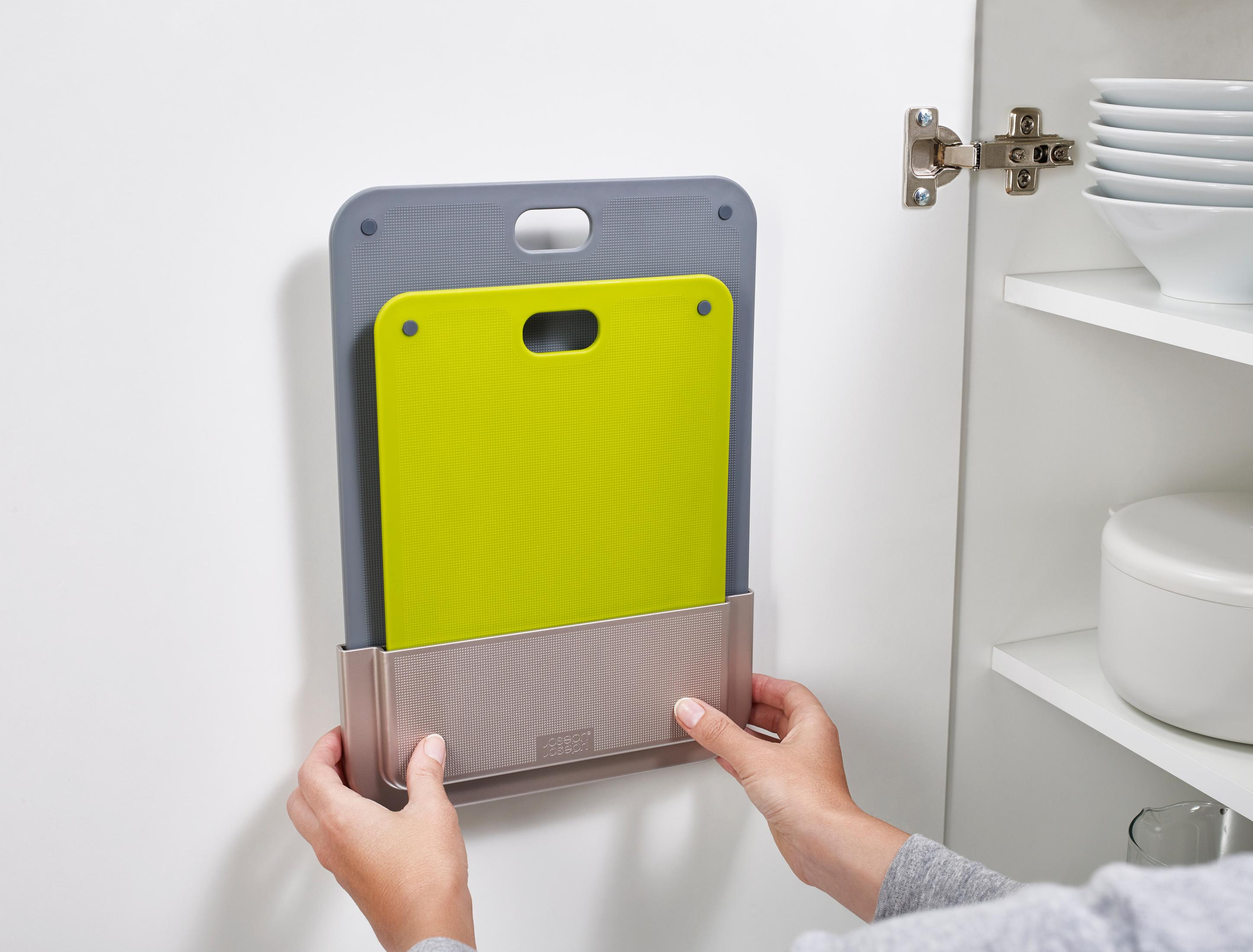 Tablas de cortar en una pared. Una persona coloca una tabla de cortar verde en un estante.