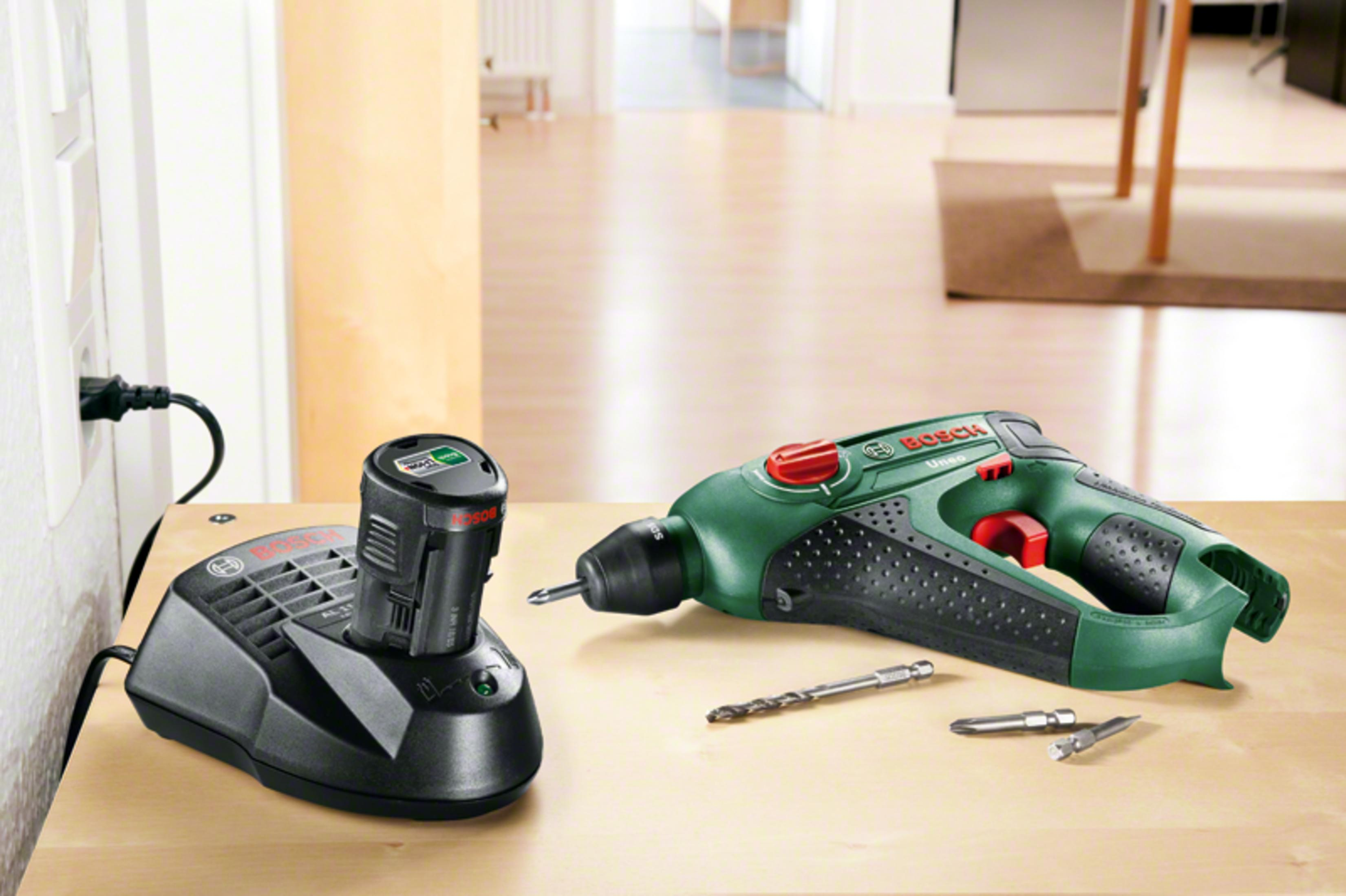 Wiertarka z ładowarką, dodatkowe bity na drewnianym stole. Gniazdo ścienne w tle.