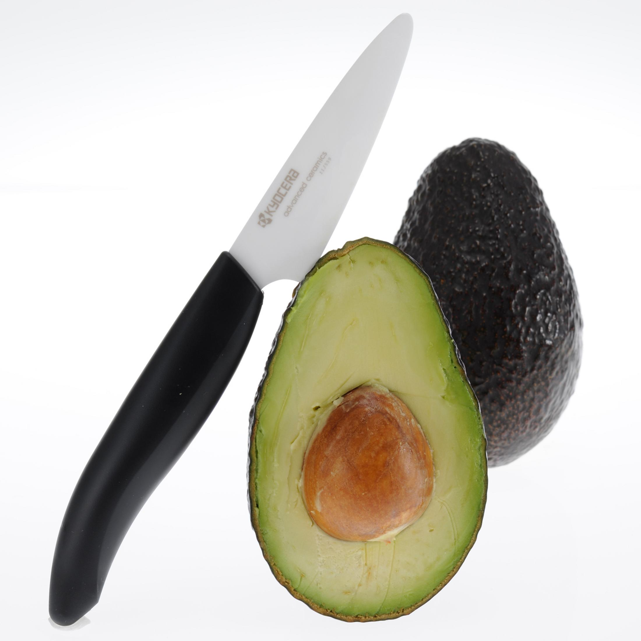 Avocado-Hälften mit Messer auf weißem Hintergrund, zeigt Samen und grünes Fruchtfleisch.