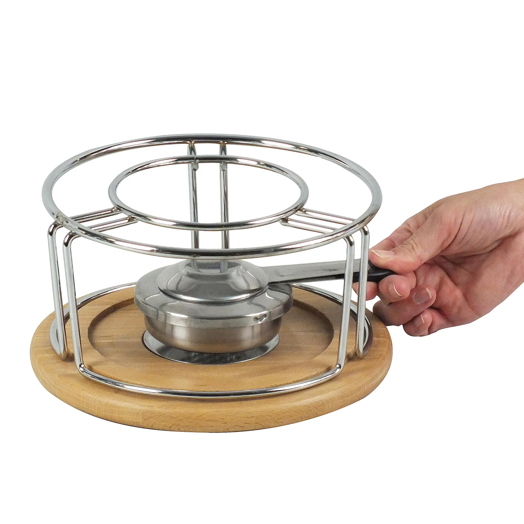 Zestaw do fondue z metalowym garnkiem i stojakiem na drewnianej podstawie, trzymany w dłoni.