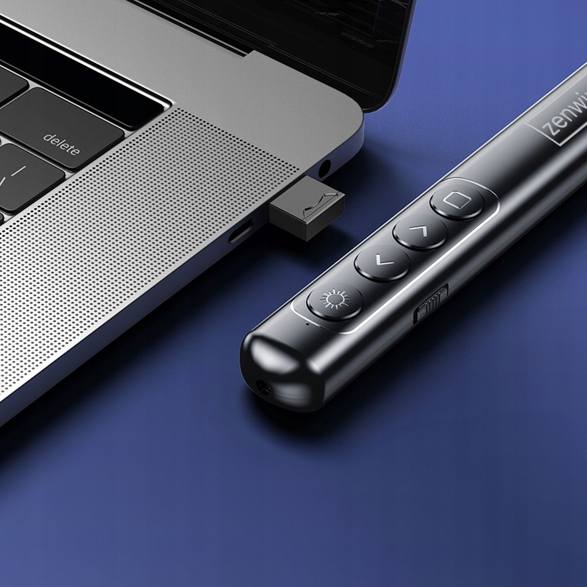 Laptop z podłączonym odbiornikiem USB i czarno-srebrnym pilotem prezentacji.