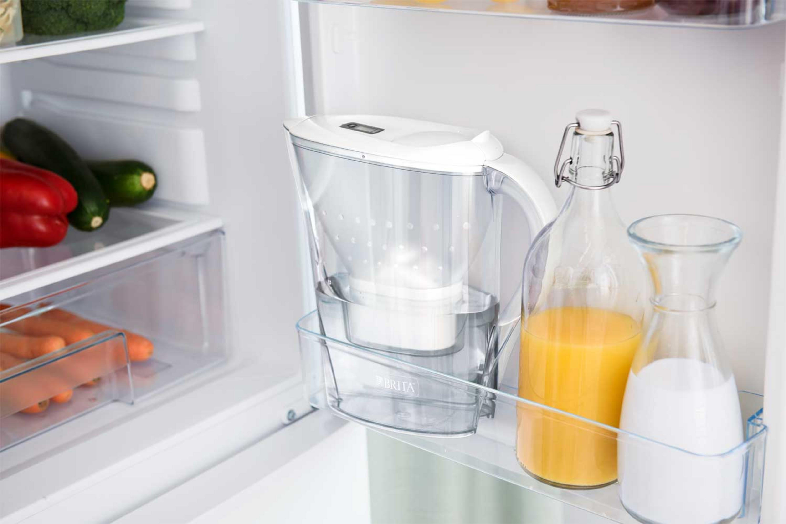 Refrigerator with a Brita water filter, orange juice, and milk bottles. The items are inside the fridge.