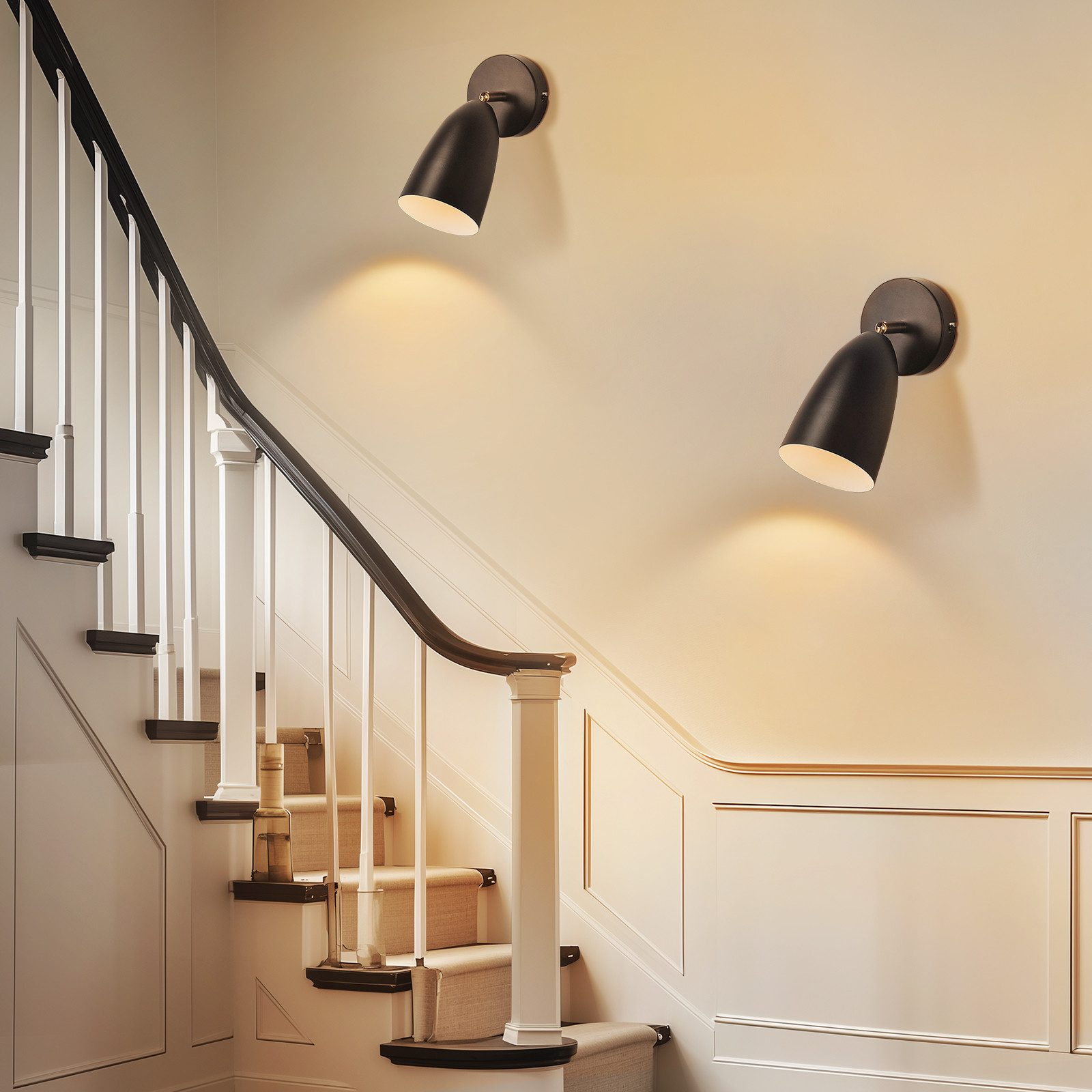 Escalera con balaustrada blanca, pasamanos negro y dos lámparas de pared negras.