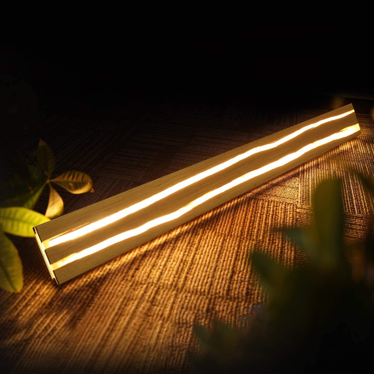 Apparecchio di illuminazione decorativo in legno, con linee di luce brillanti, su una superficie marrone scuro.