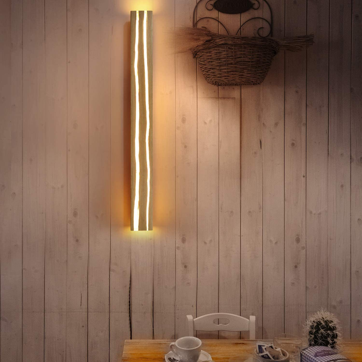 Muro in legno con lampada verticale e cestino sospeso. Tavolo e sedia di fronte.