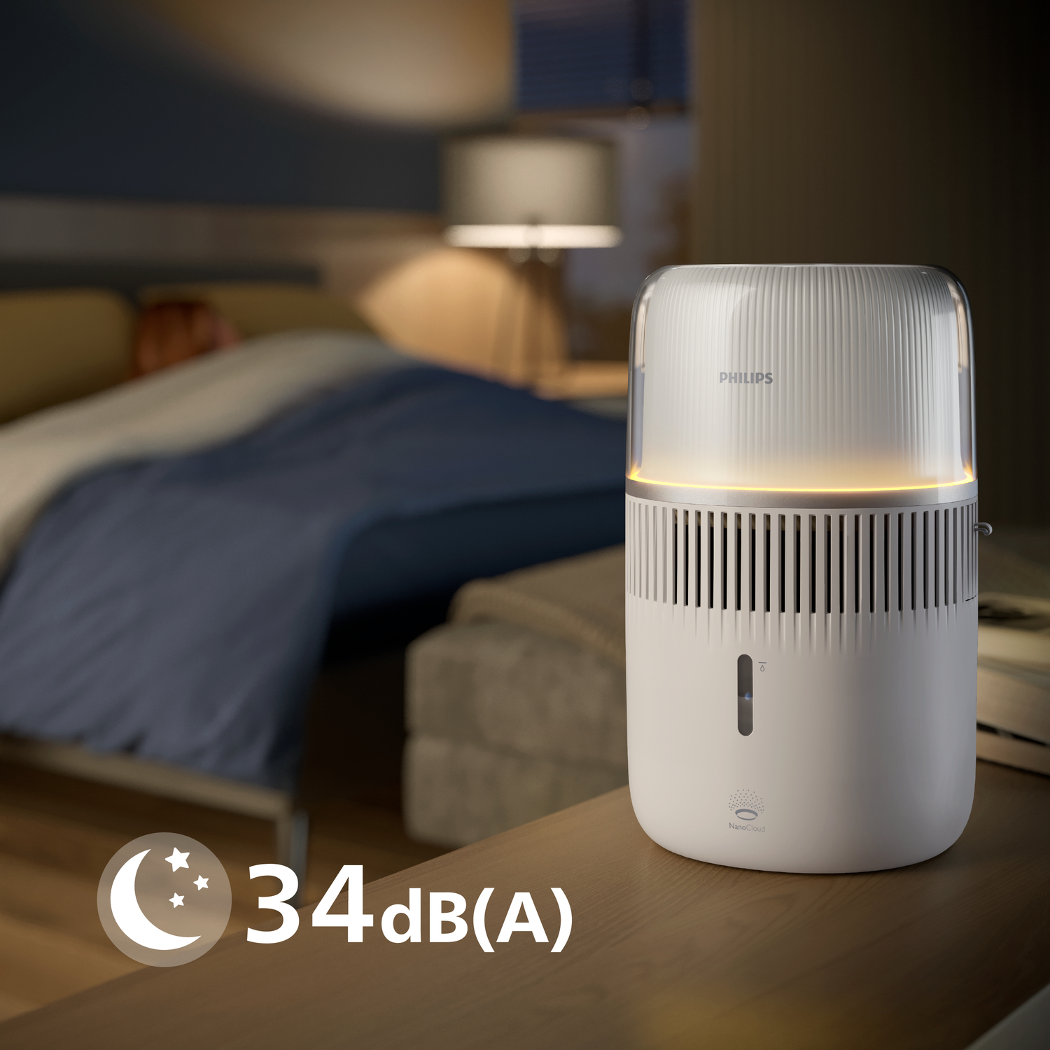 Luftreiniger auf einem Tisch. Der Raum ist dunkel, mit einem Bett und einer Lampe. Der Text lautet '34dB(A)'.