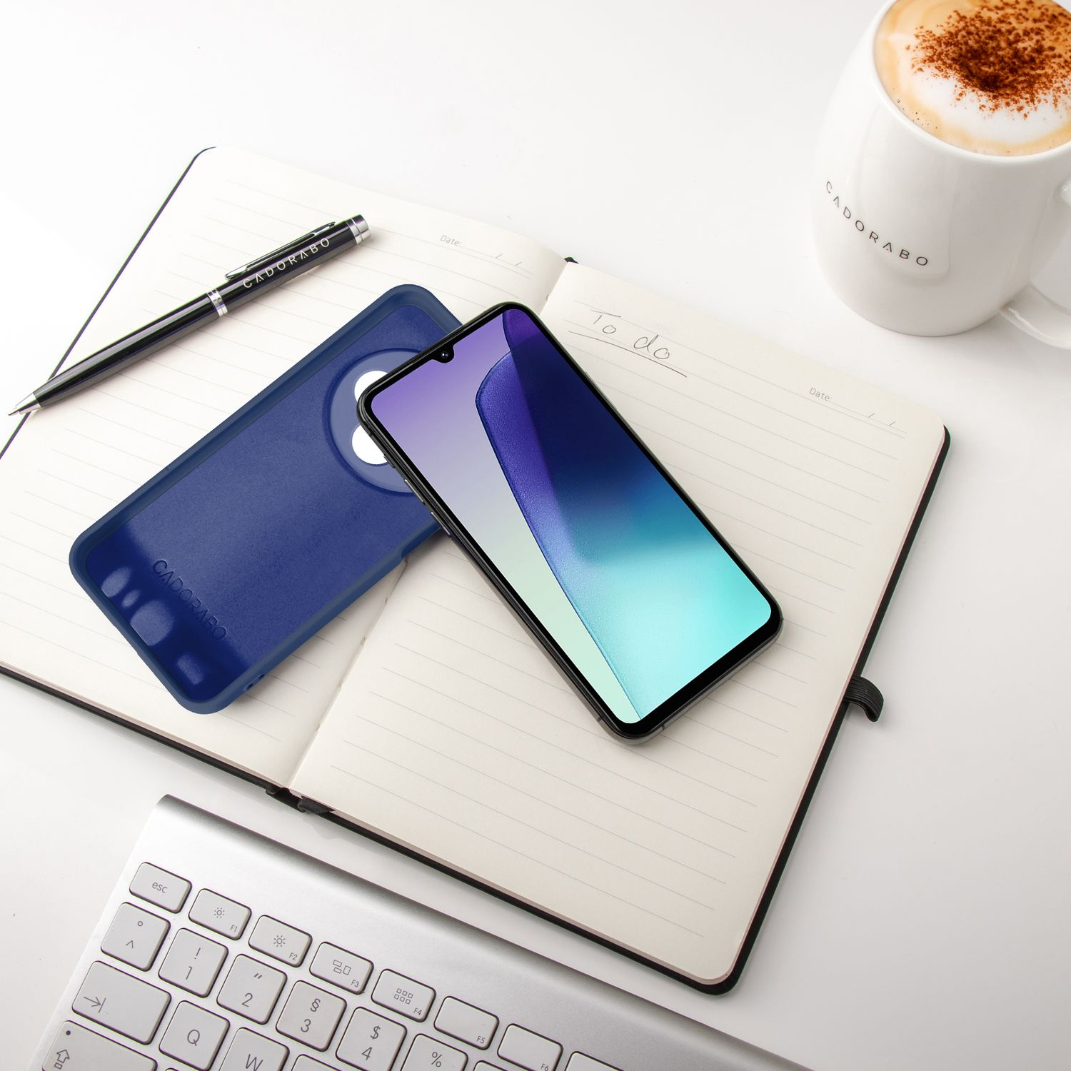 Smartphone und schwarze Handyhülle auf Notizblock. Stift und Kaffeetasse auf dem weißen Tisch.