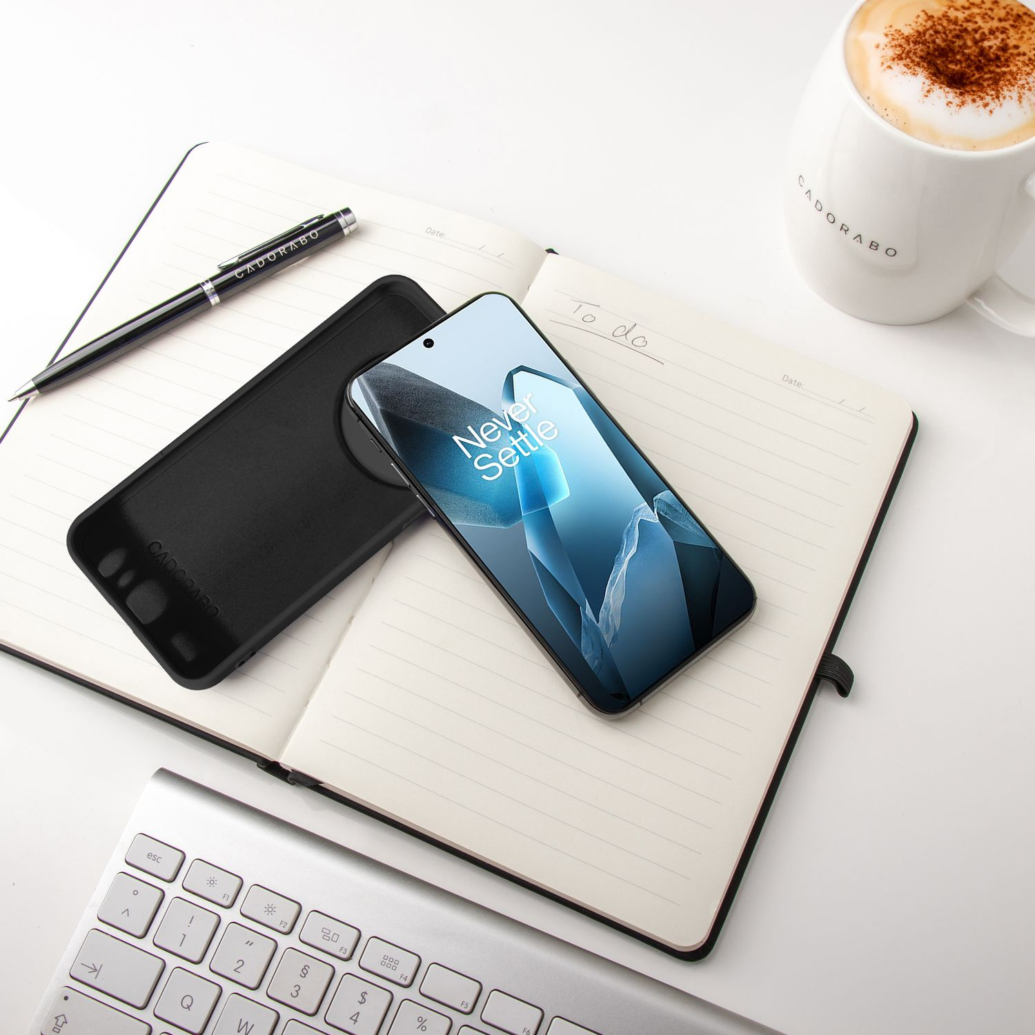 Telefon und Hülle auf Notizblock. Stift, Tastatur und Kaffeetasse auf dem Schreibtisch.