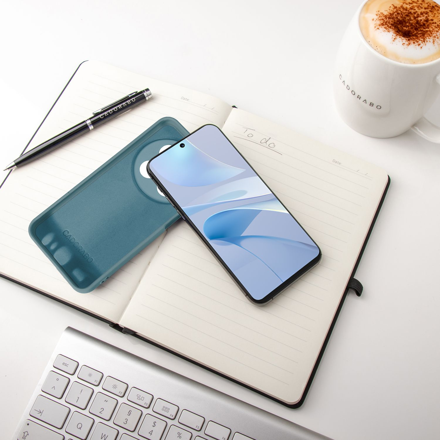Notizbuch mit Stift, Telefon, Hülle und Kaffeetasse. To-Do-Liste ist geschrieben.