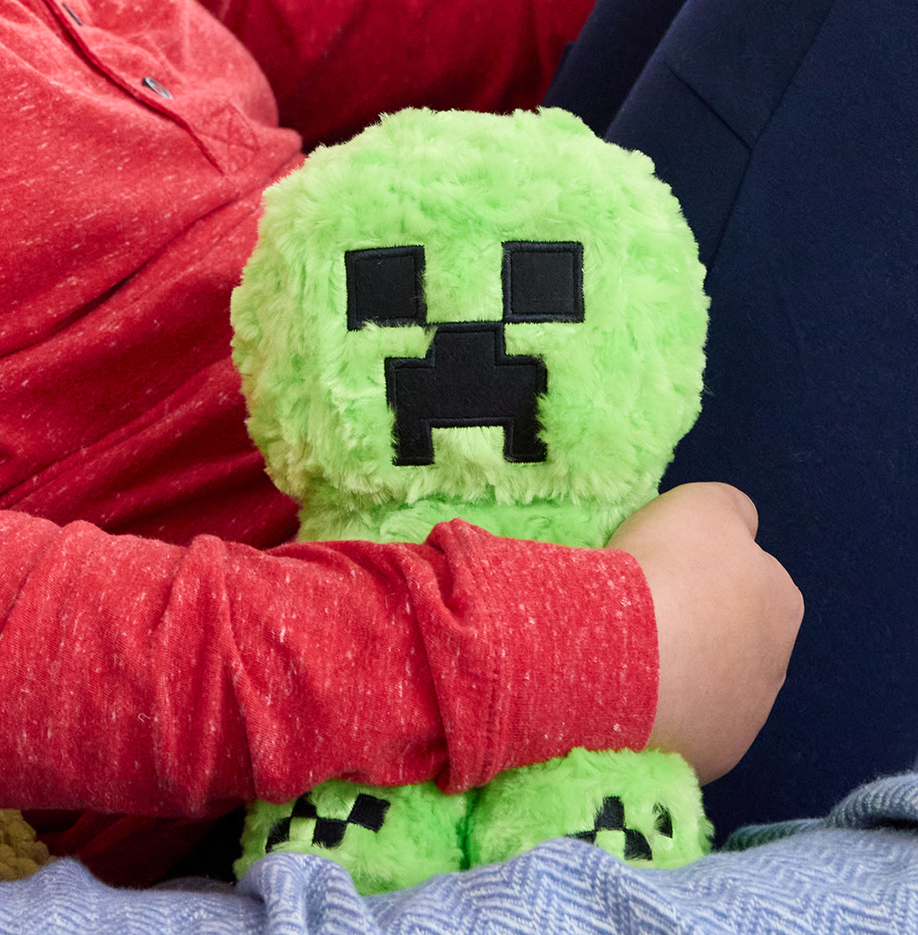Un peluche verde Creeper di Minecraft tenuto da una persona.