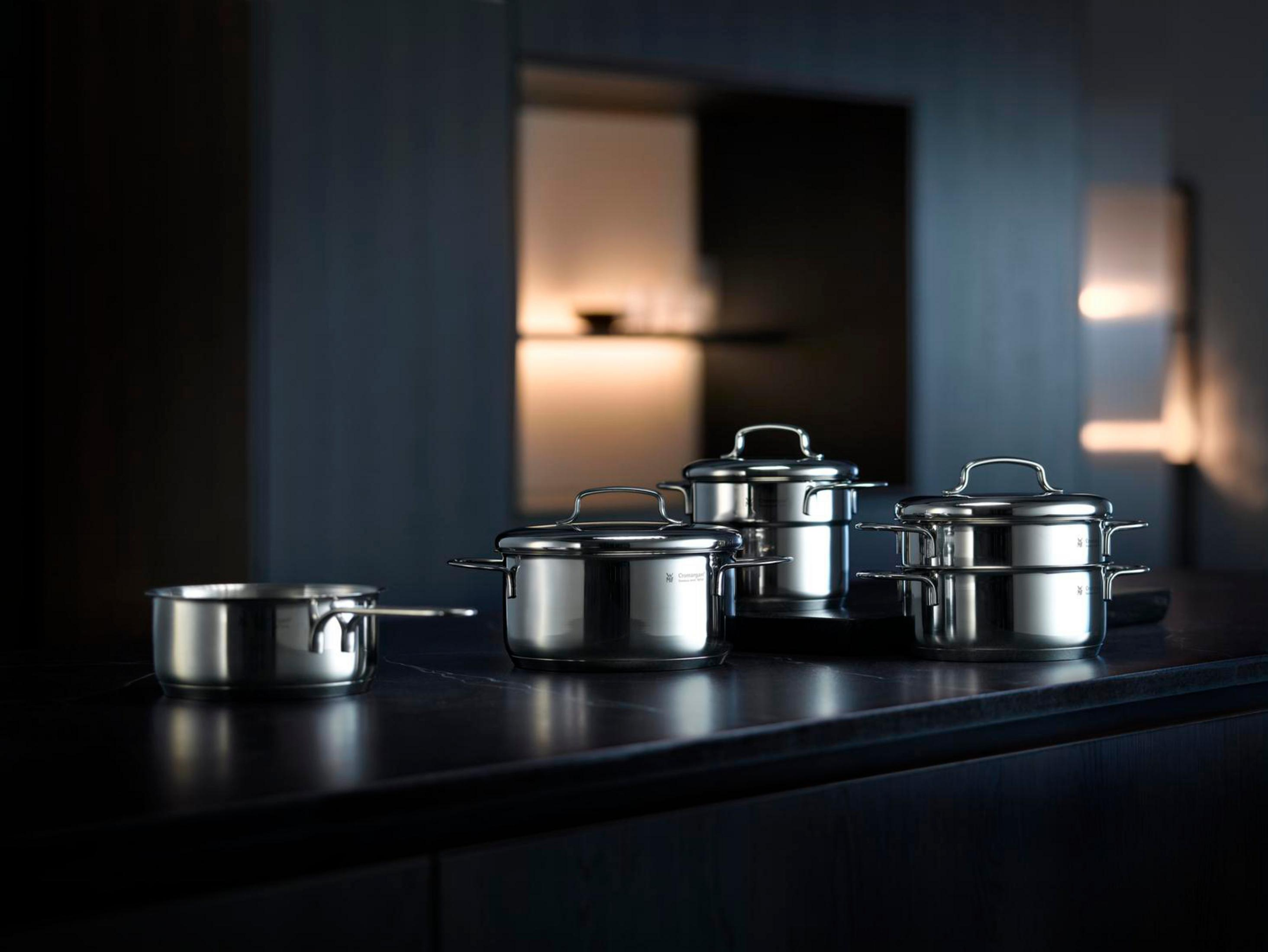 Casseroles en acier inoxydable sur une surface sombre. Intérieur avec placards en arrière-plan.