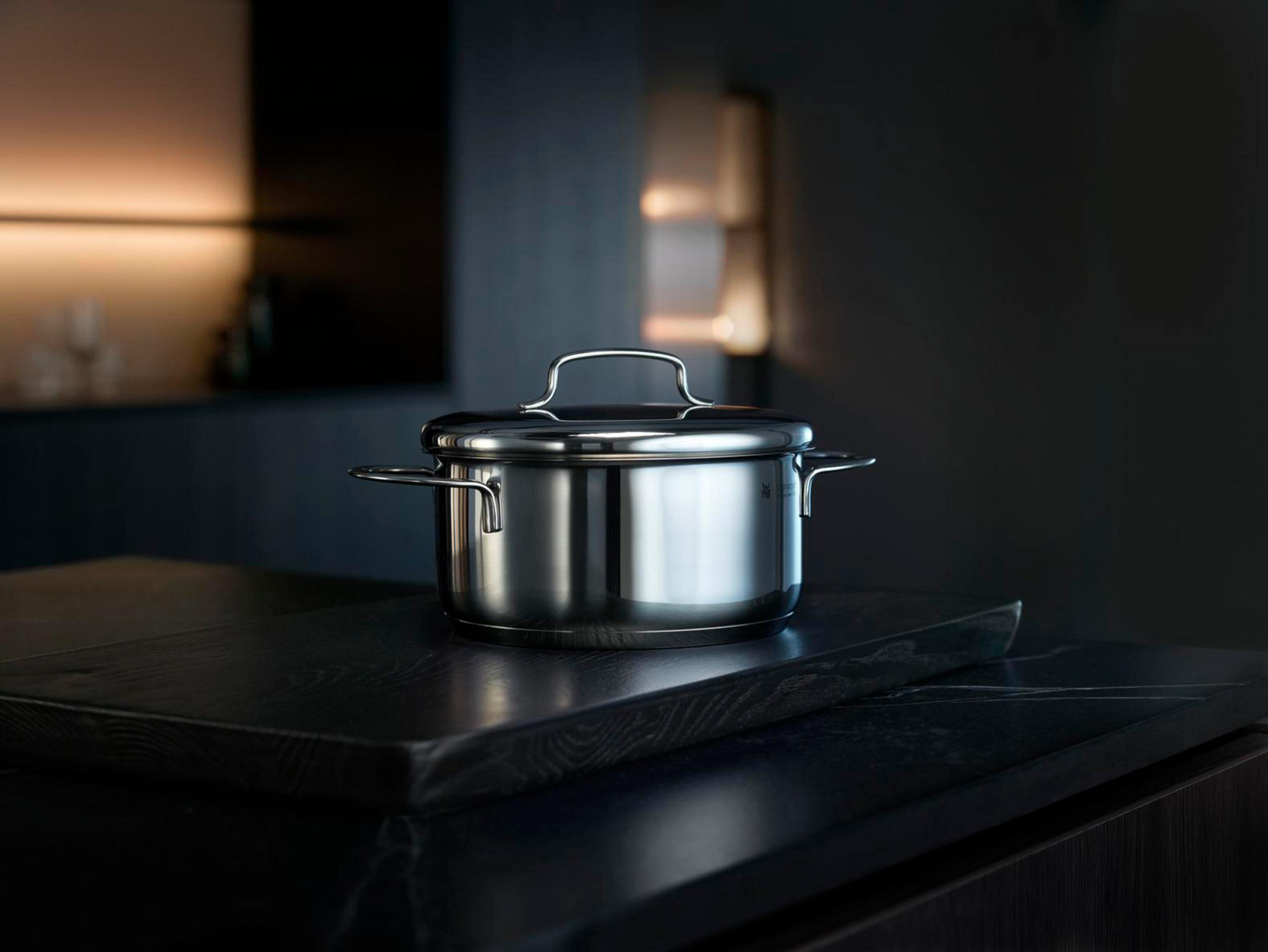 Casserole en acier inoxydable sur une surface noire. Fond sombre, ambiance cuisine.