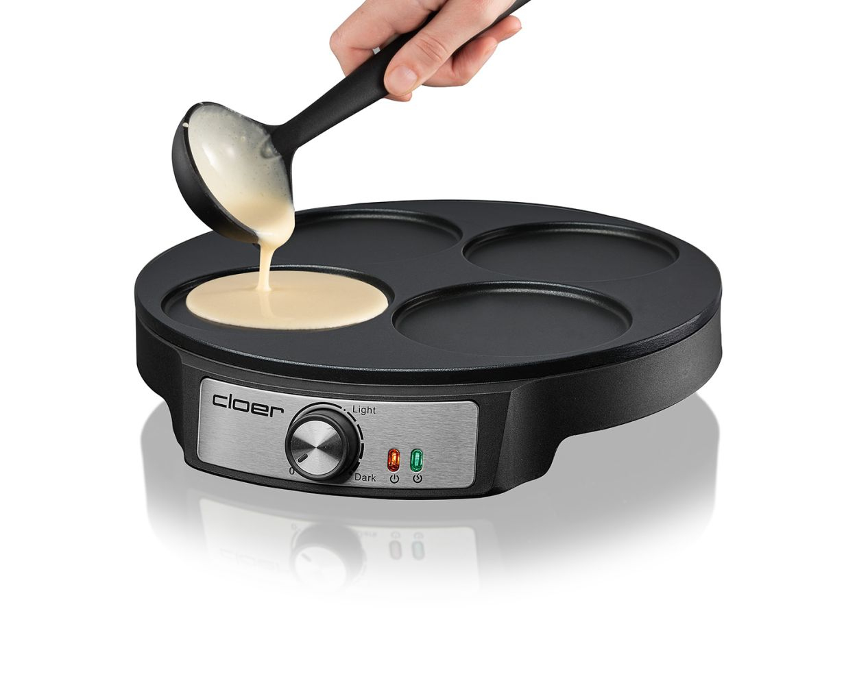 Una persona versa la pastella su una macchina per pancake nera con quattro stampi circolari.
