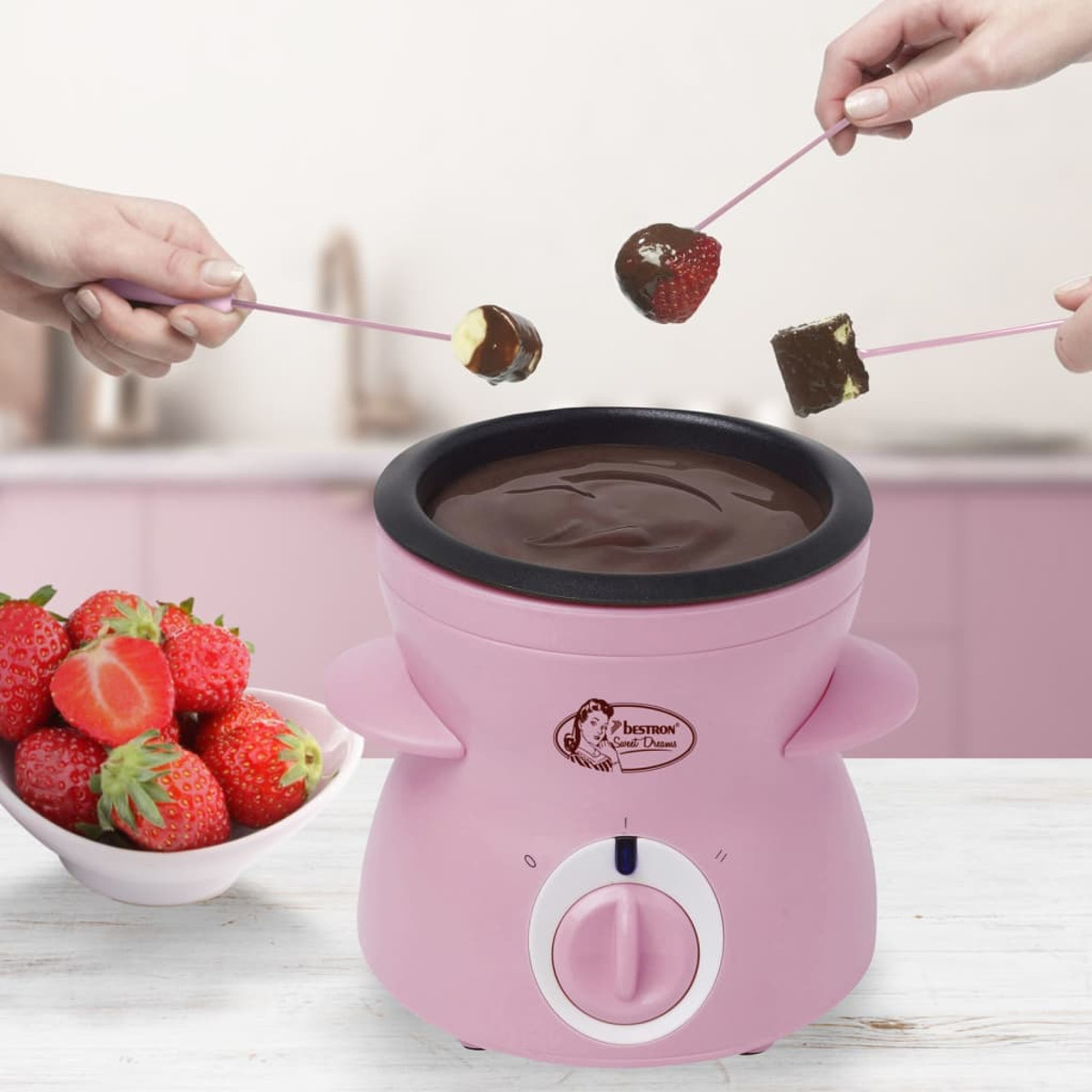 Różowy garnek do fondue czekoladowego z truskawkami i zanurzonymi produktami.