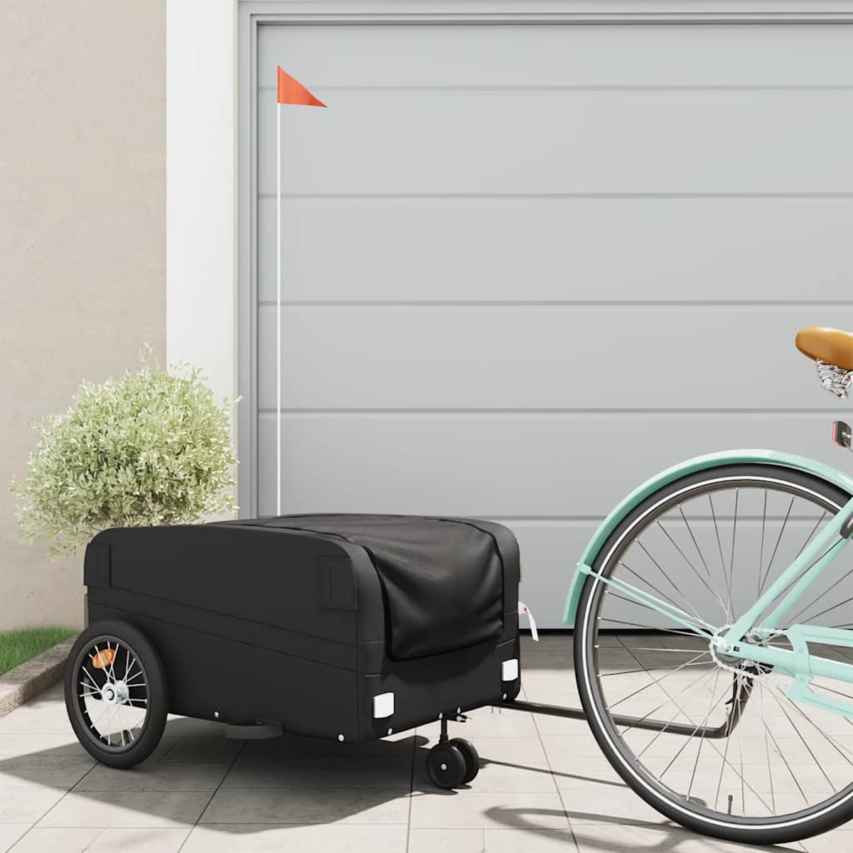 Schwarzer Fahrradanhänger an einem Fahrrad. Garage im Hintergrund, orange Fahne. Sonniger Tag.