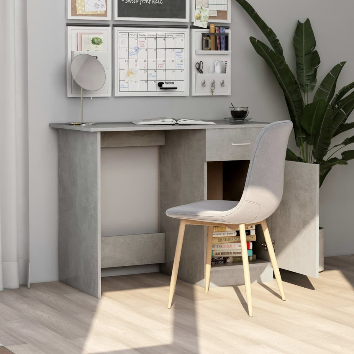 Schreibtisch mit Stuhl, offener Schublade, Monitor und Zubehör vor Wand mit Dekoration.