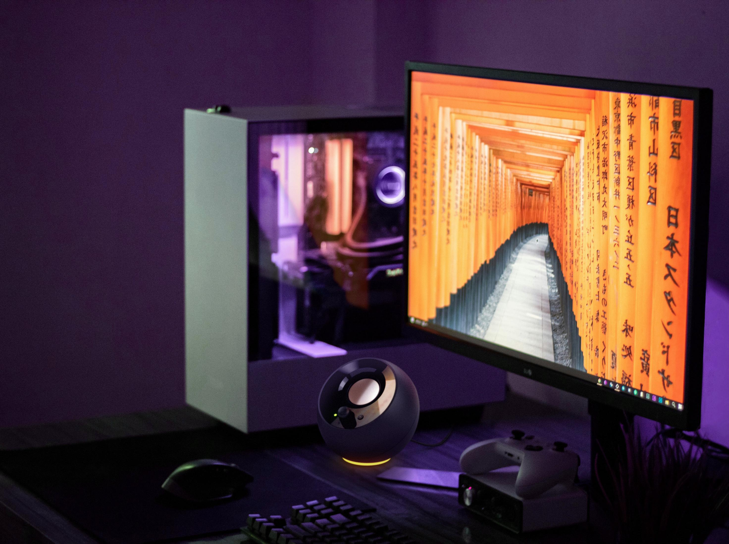 Konfiguracja komputera na biurku z monitorem, głośnikiem, klawiaturą i komputerem, fioletowy.