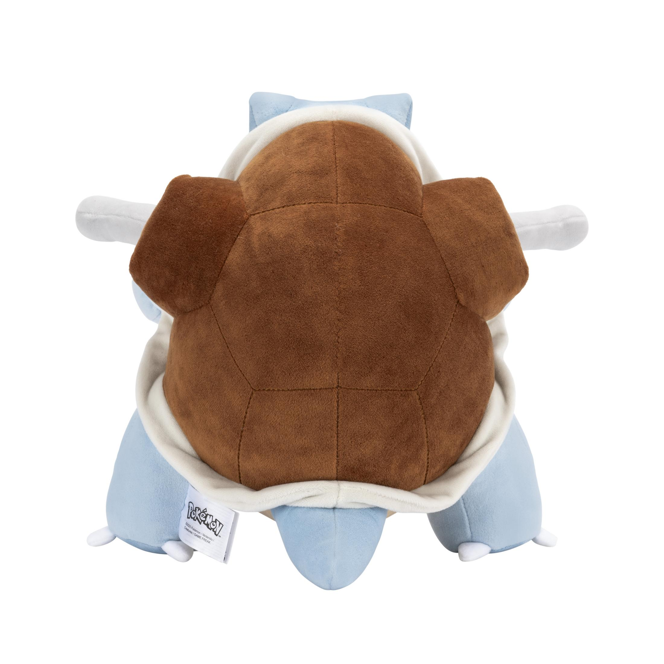Le dos d'une peluche Blastoise Pokemon. Il est bleu, marron et crème, avec une étiquette attachée.