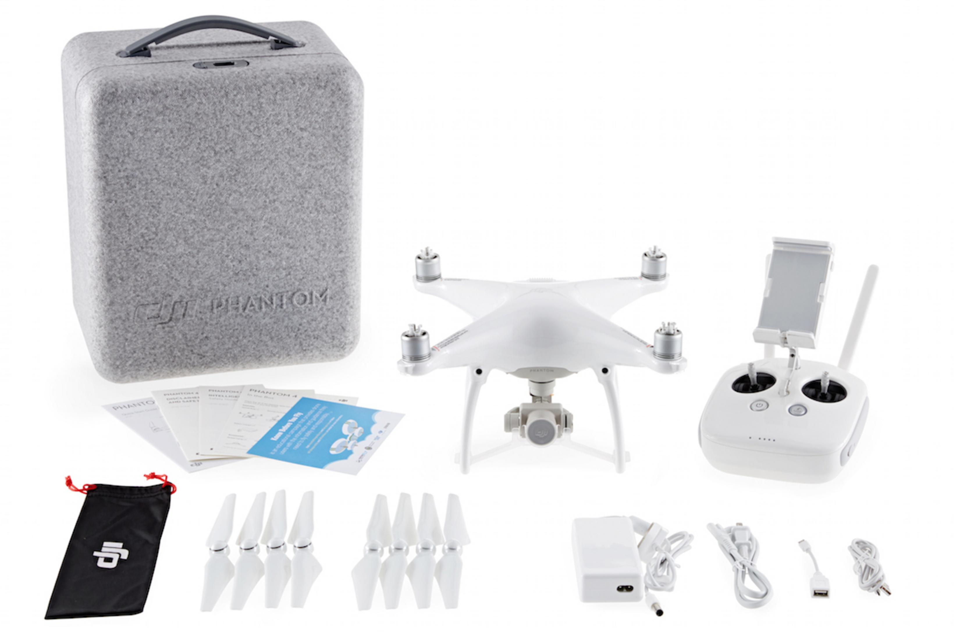 Ein Drohnen-Kit mit einer weißen Drohne, einem grauen Koffer und mehreren Zubehörteilen auf einer weißen Oberfläche. Der Koffer sagt 'DJI Phantom'.