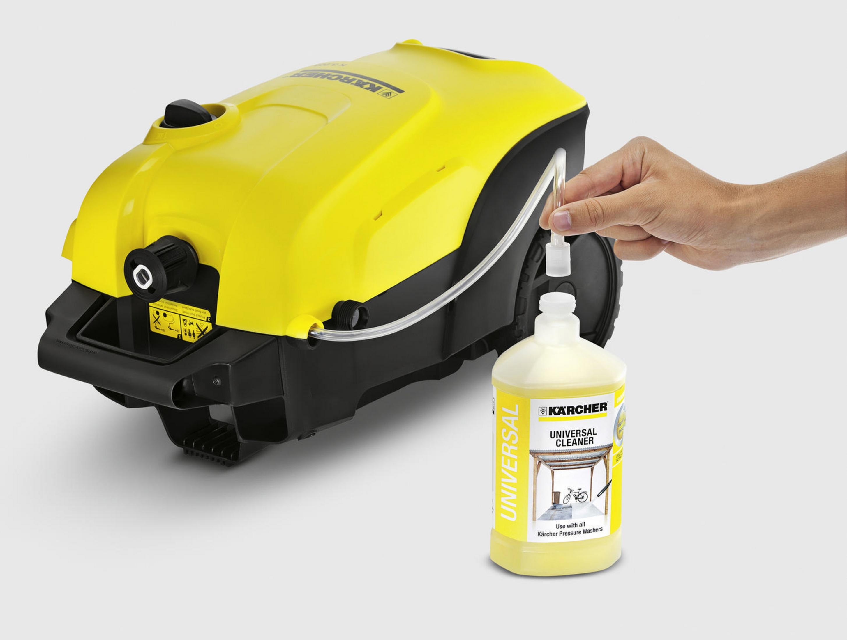 Yellow pressure washer and a bottle of cleaner. A hand is holding the cleaner. White background.