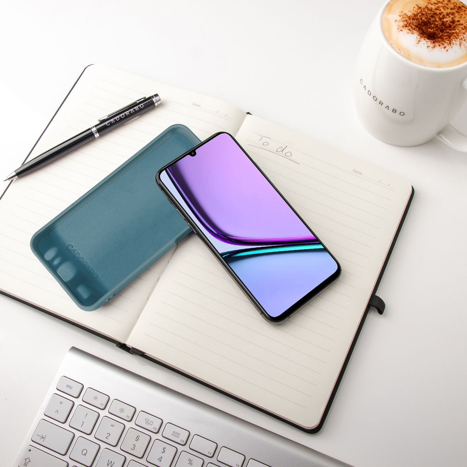 Ein Notizbuch mit Telefon und Stift. Außerdem eine Kaffeetasse und eine Tastatur.