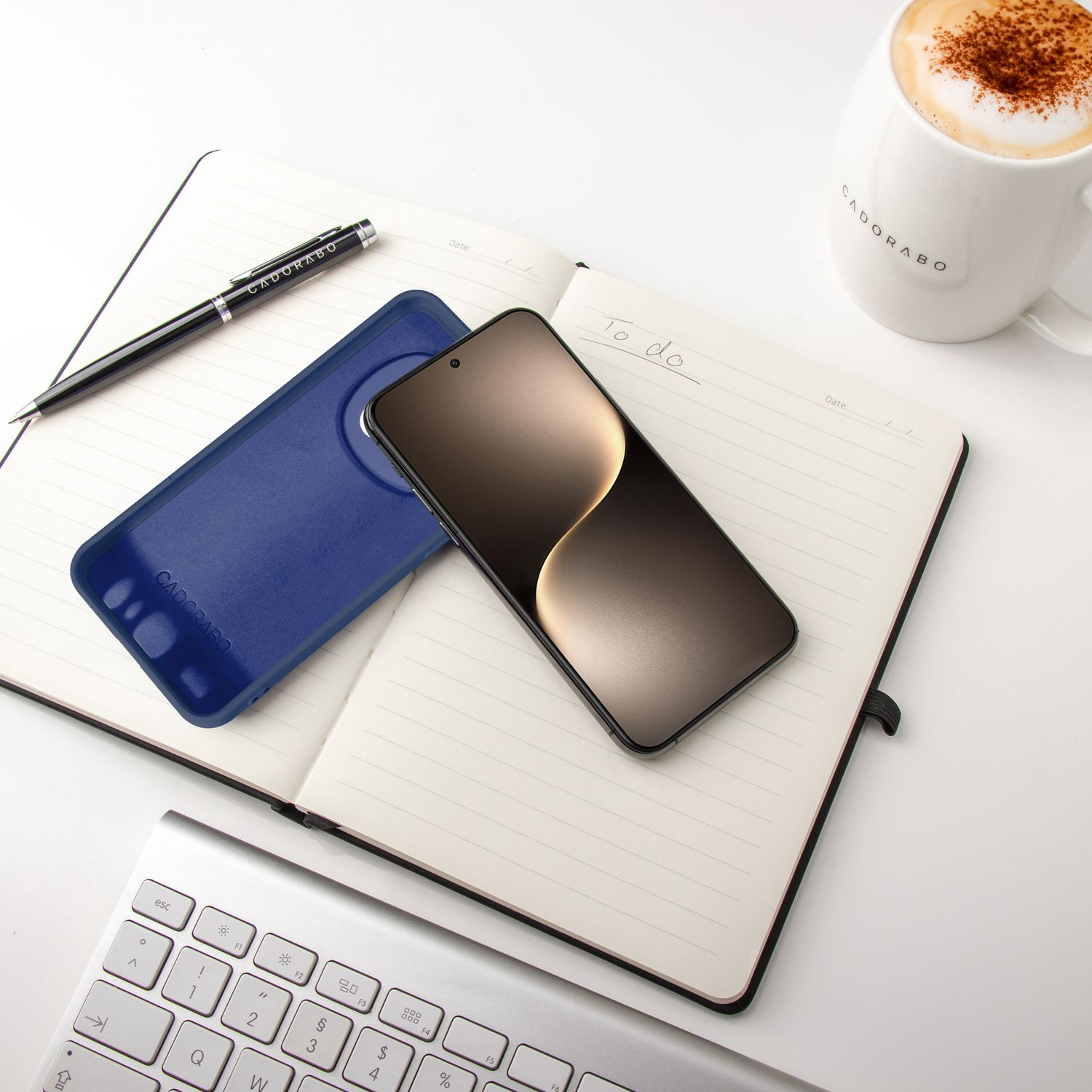 Notizbuch mit Telefon, Hülle, Stift und Kaffeetasse auf dem Schreibtisch.