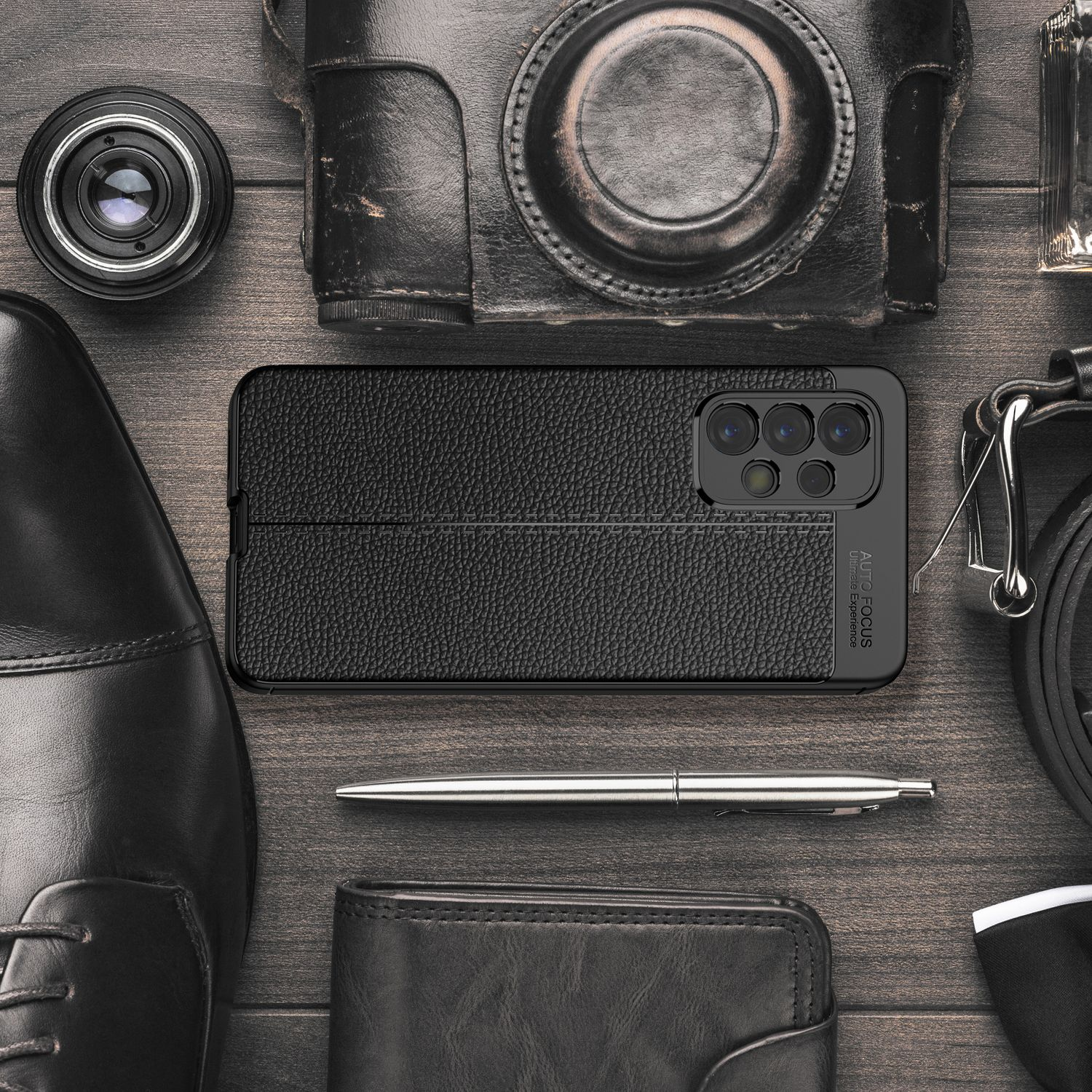 Schwarze Leder-Handyhülle mit schwarzem Telefon darin. Mehrere Accessoires auf einem Holztisch.