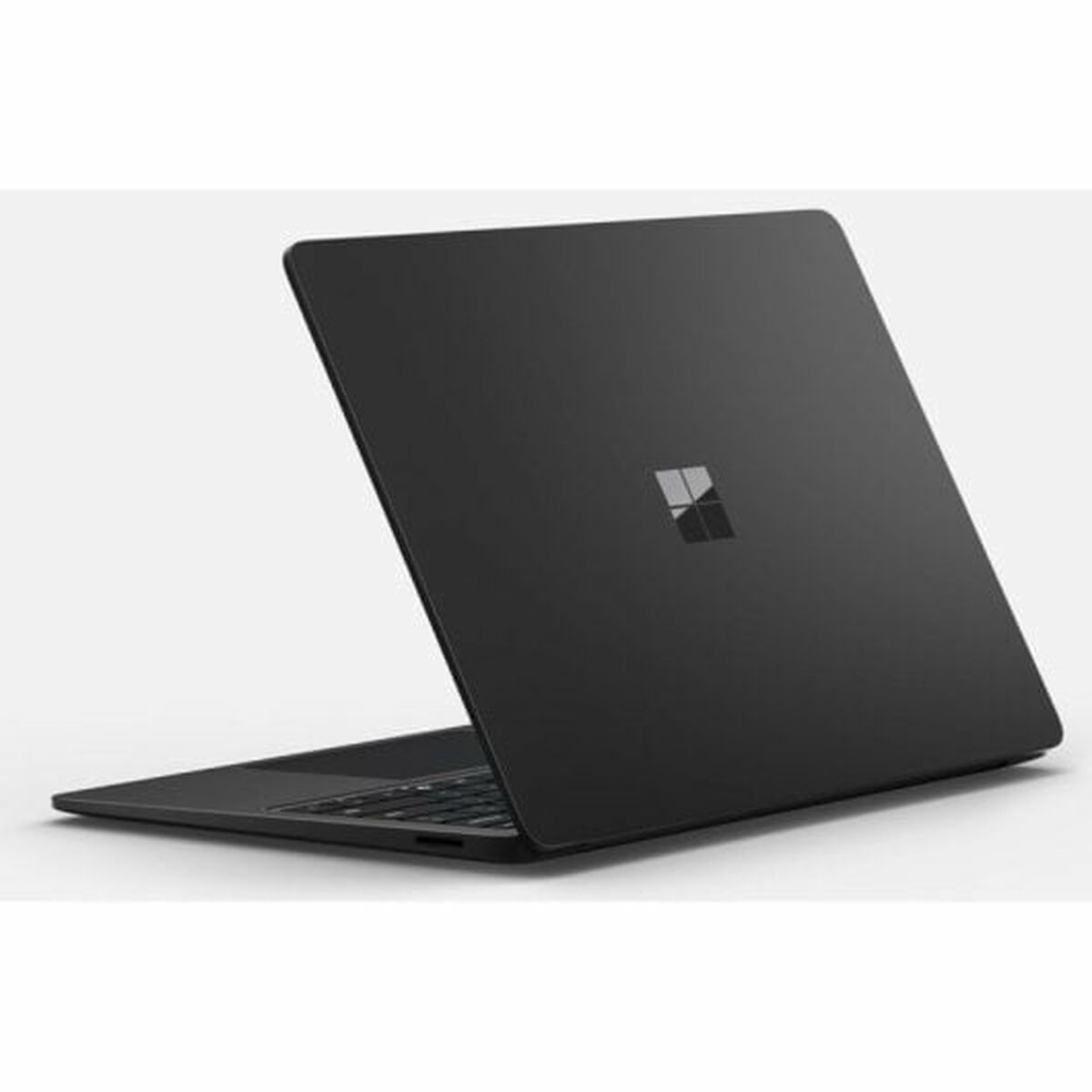 Laptop negro en superficie blanca, ligeramente abierto, mostrando pantalla con logo Windows.