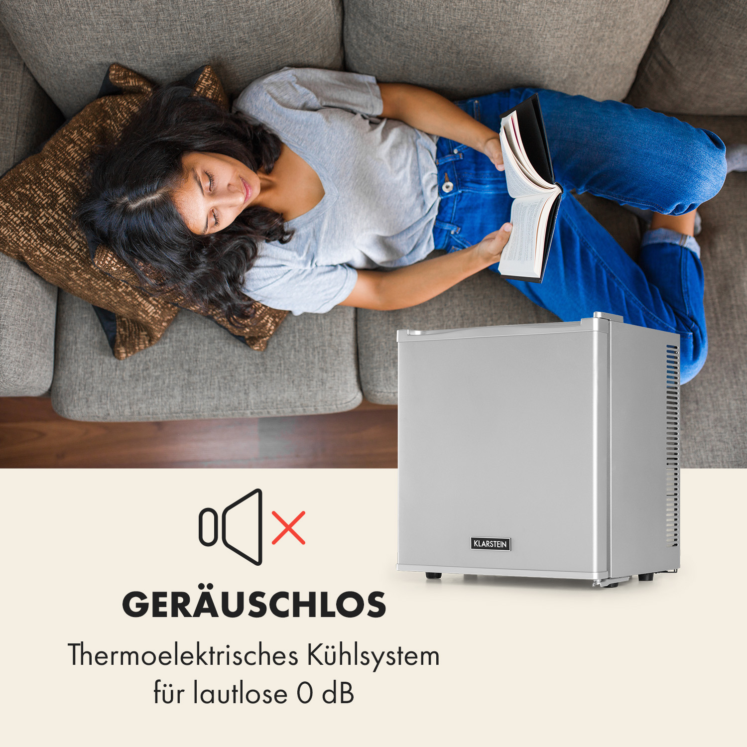 Frau liest Buch auf Couch, kleiner silberner Kühlschrank im Hintergrund.