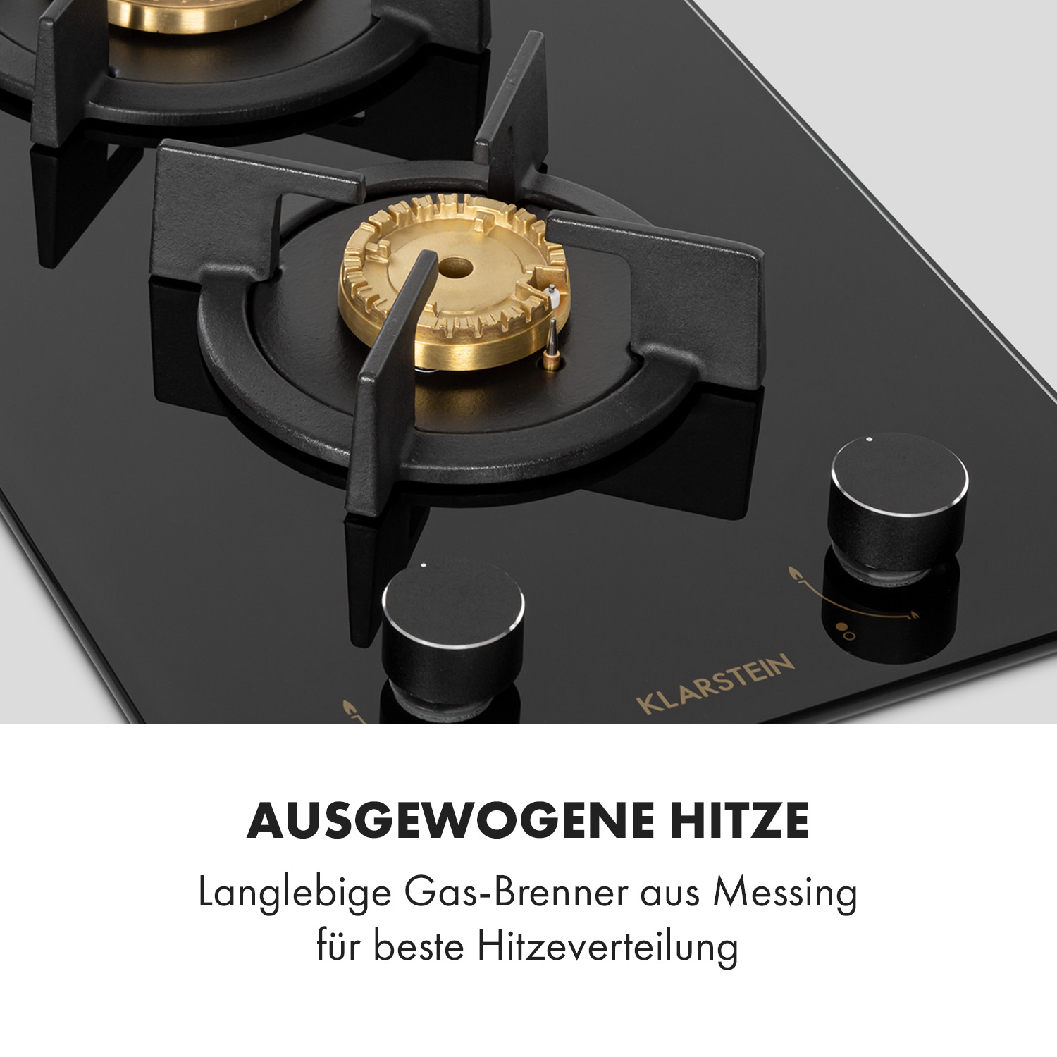 Nahaufnahme eines schwarzen Gasherds mit zwei Brennern und schwarzen Knöpfen. Der Text 'AUSGEWOGENE HITZE' steht darunter.