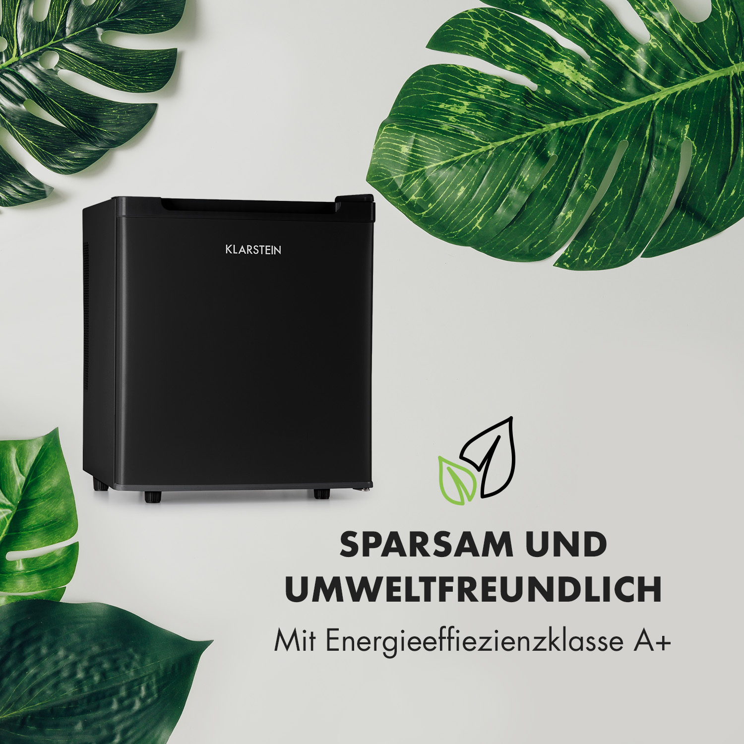 Schwarzer Mini-Kühlschrank mit Text: Sparsam und Umweltfreundlich. Grüne Blätter.