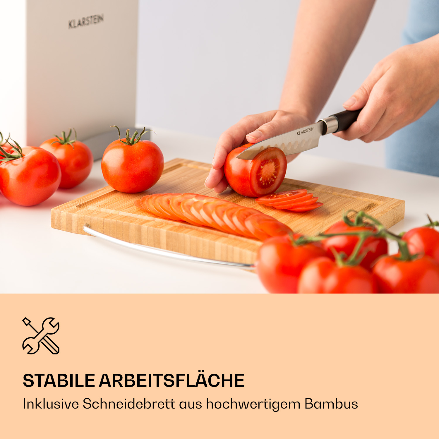 Eine Person schneidet eine Tomate auf einem Holzschneidebrett, mit Tomaten im Vordergrund.